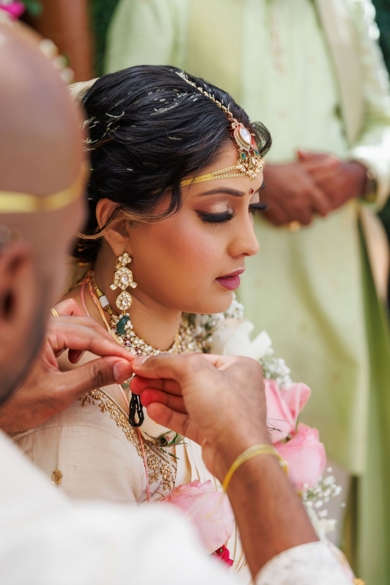 A beautifully adorned Indian bride receives a necklace during her traditional Hindu wedding ceremony.