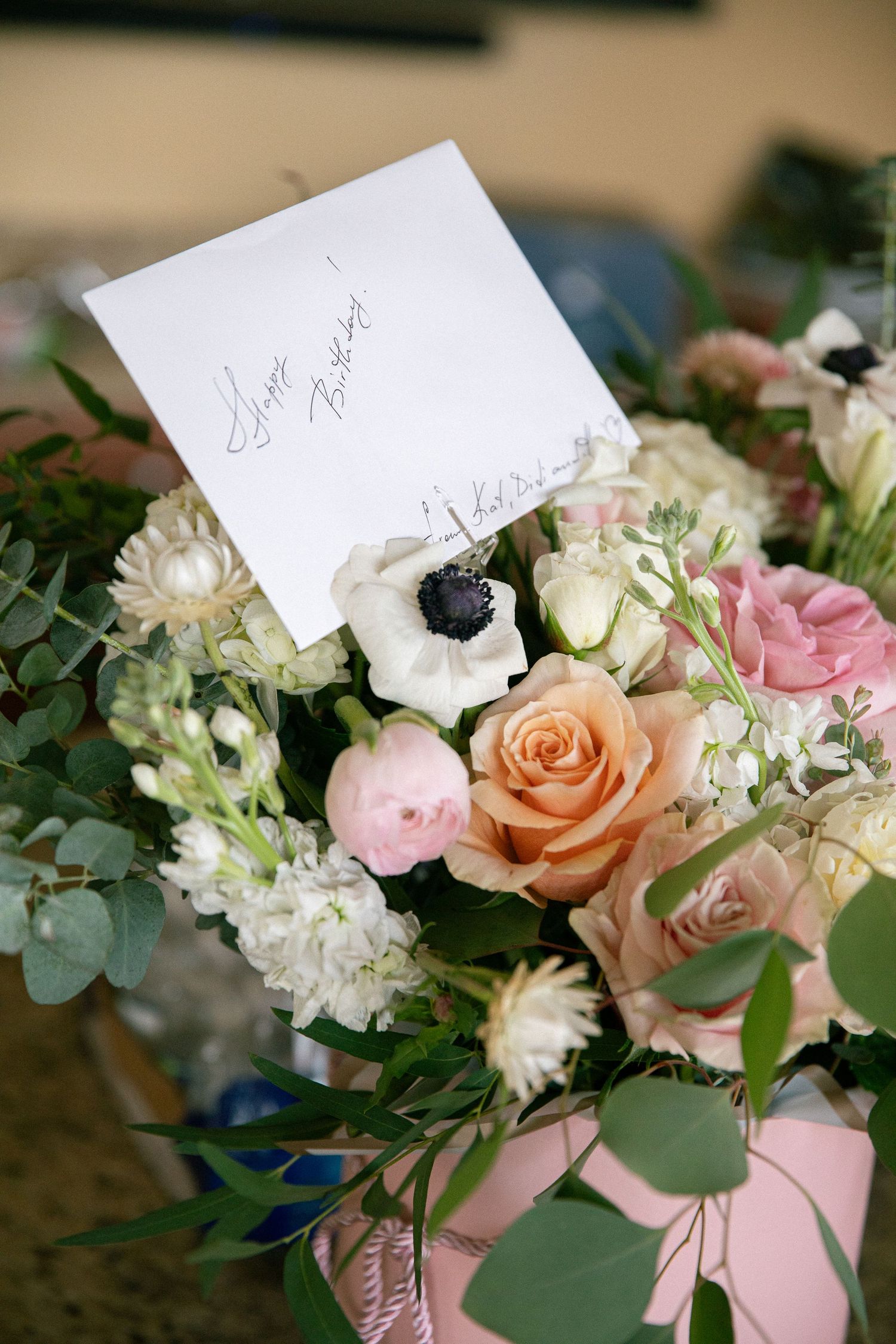 Floral arrangement featuring pink roses, white hydrangeas and eucalyptus with name cards.