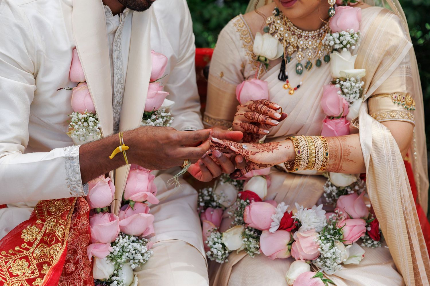 Indian couple exchanging rings during traditional Hindu wedding ceremony with floral garlands.