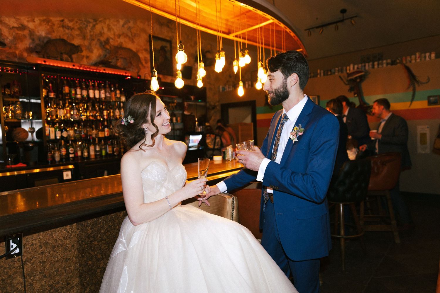 A couple dancing together in a dimly lit venue with hanging lights and a bar in the background.