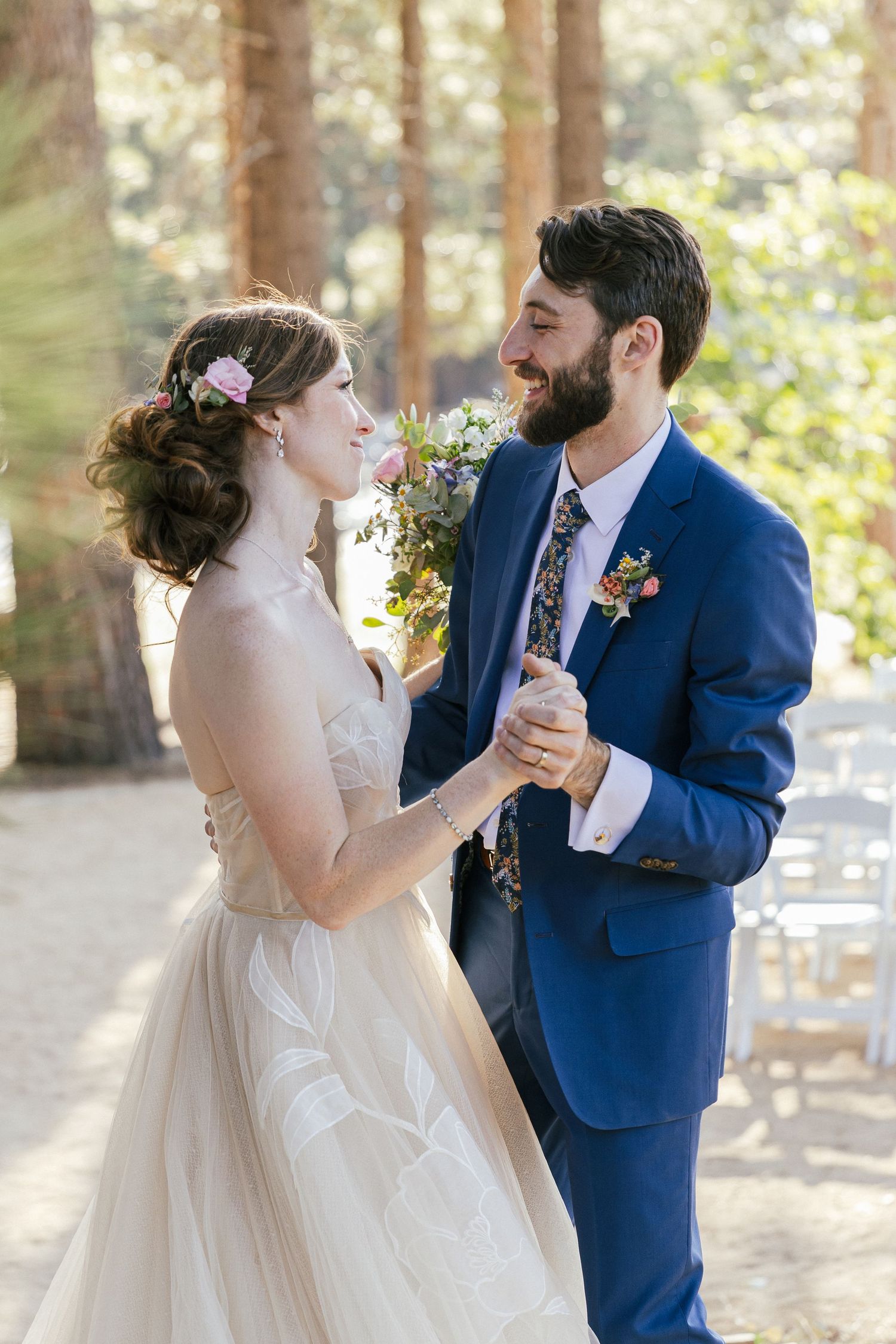 Couple shares their first dance outdoors with pine trees in the background.