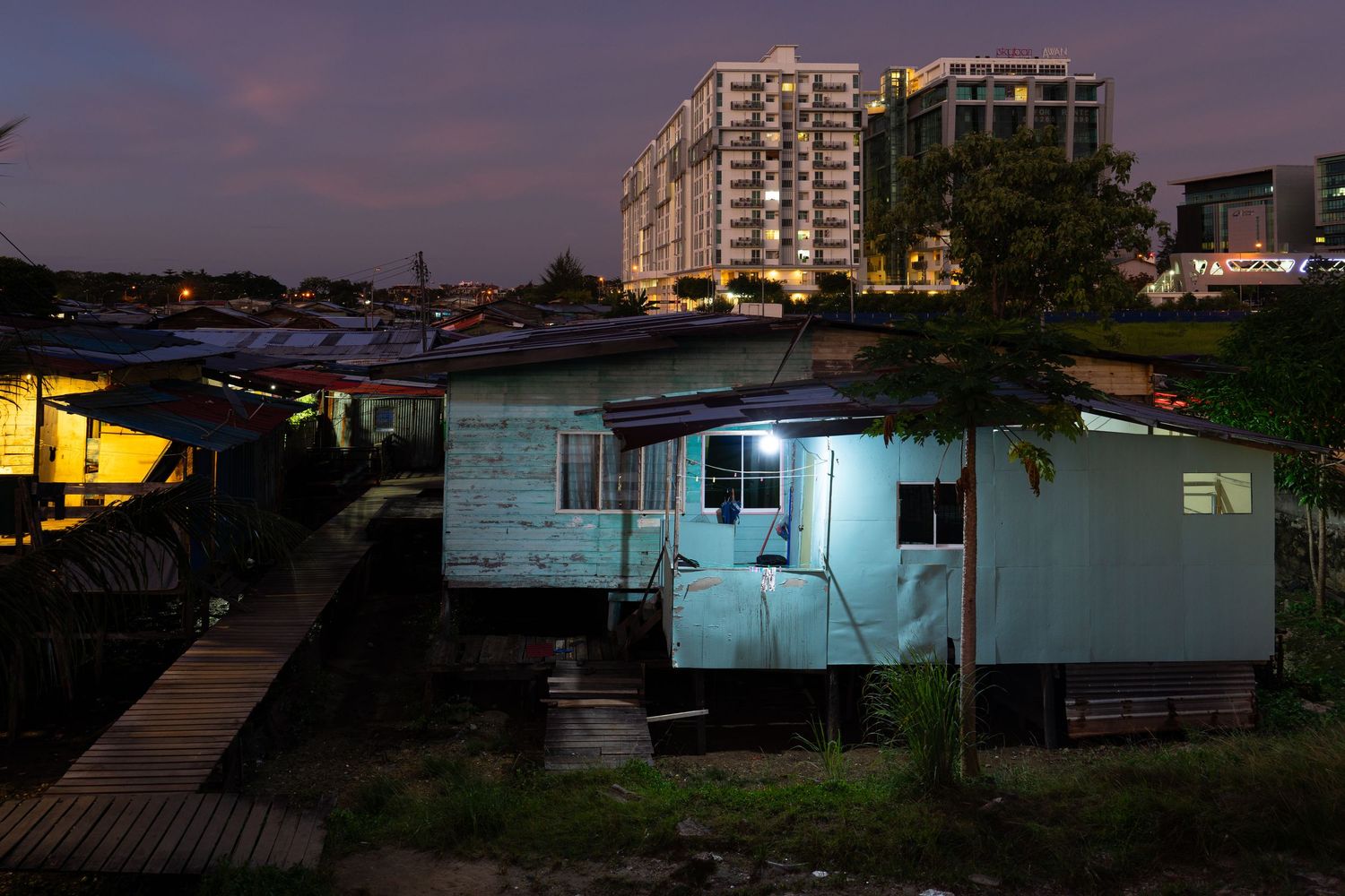 A dawn view of a traditional wooden house in Kampung Sembulan that still remains amidst rapid urban development surrounding it
