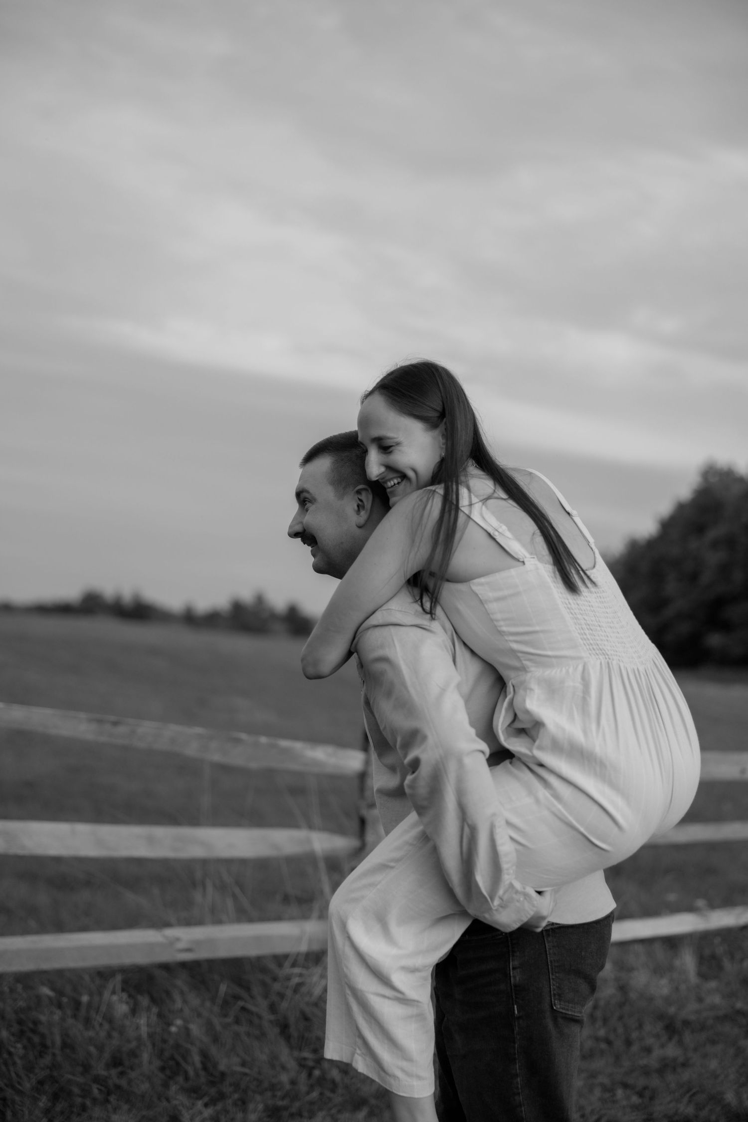 A romantic black and white photo sequence shows a couple embracing in a field beside a wooden fence.