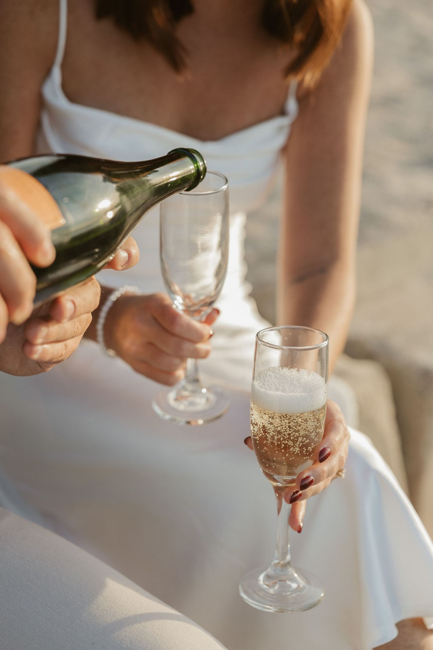 Someone pours sparkling wine into elegant crystal glasses at a formal event.