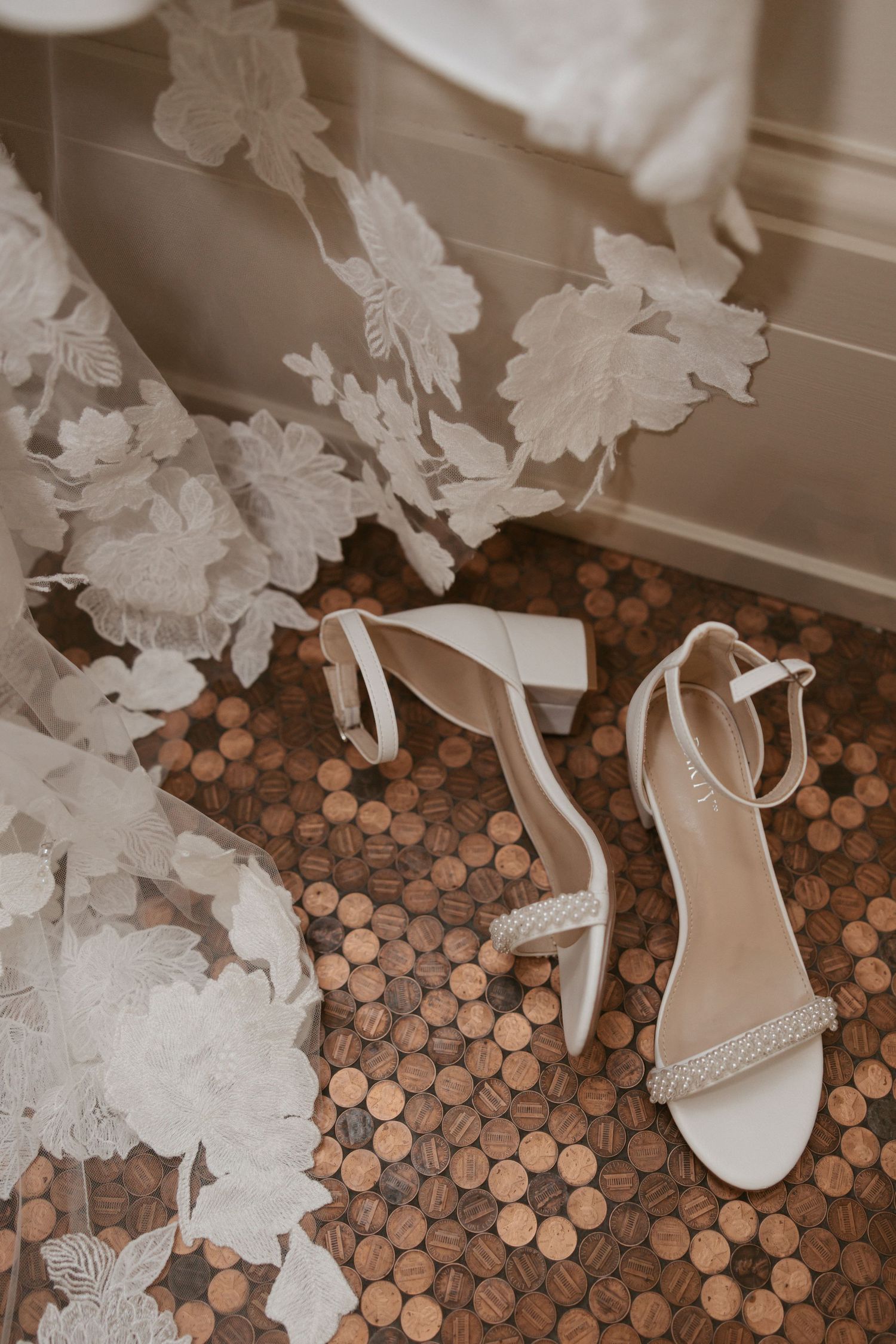 Wedding shoes and decorative white butterflies arranged on a floor made of copper pennies create an artistic composition.