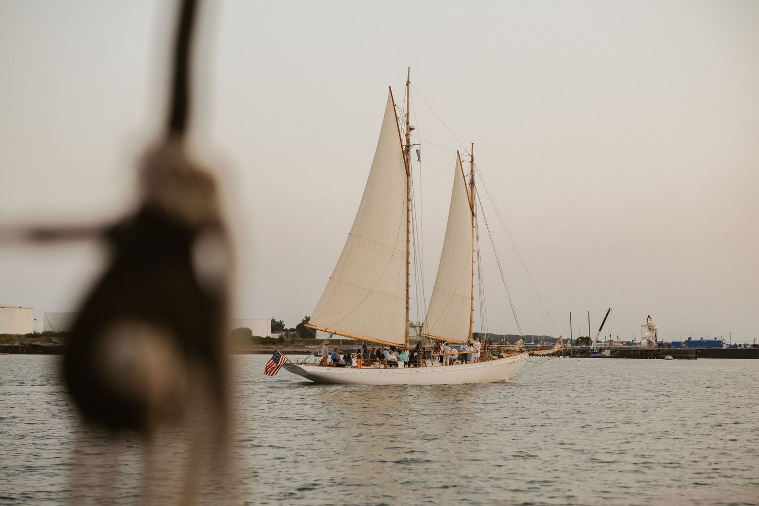 Vintage sailing vessels with billowing white sails glide across calm waters in a sepia-toned maritime scene.