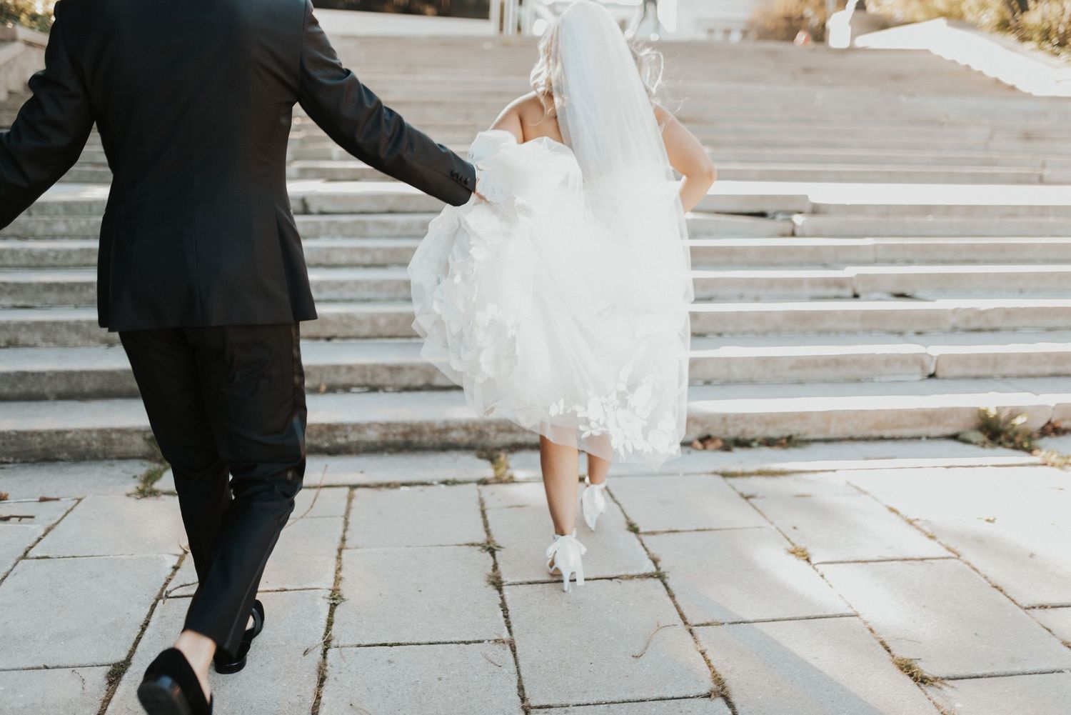 A couple in wedding attire walks together on stone steps during their special day celebration.