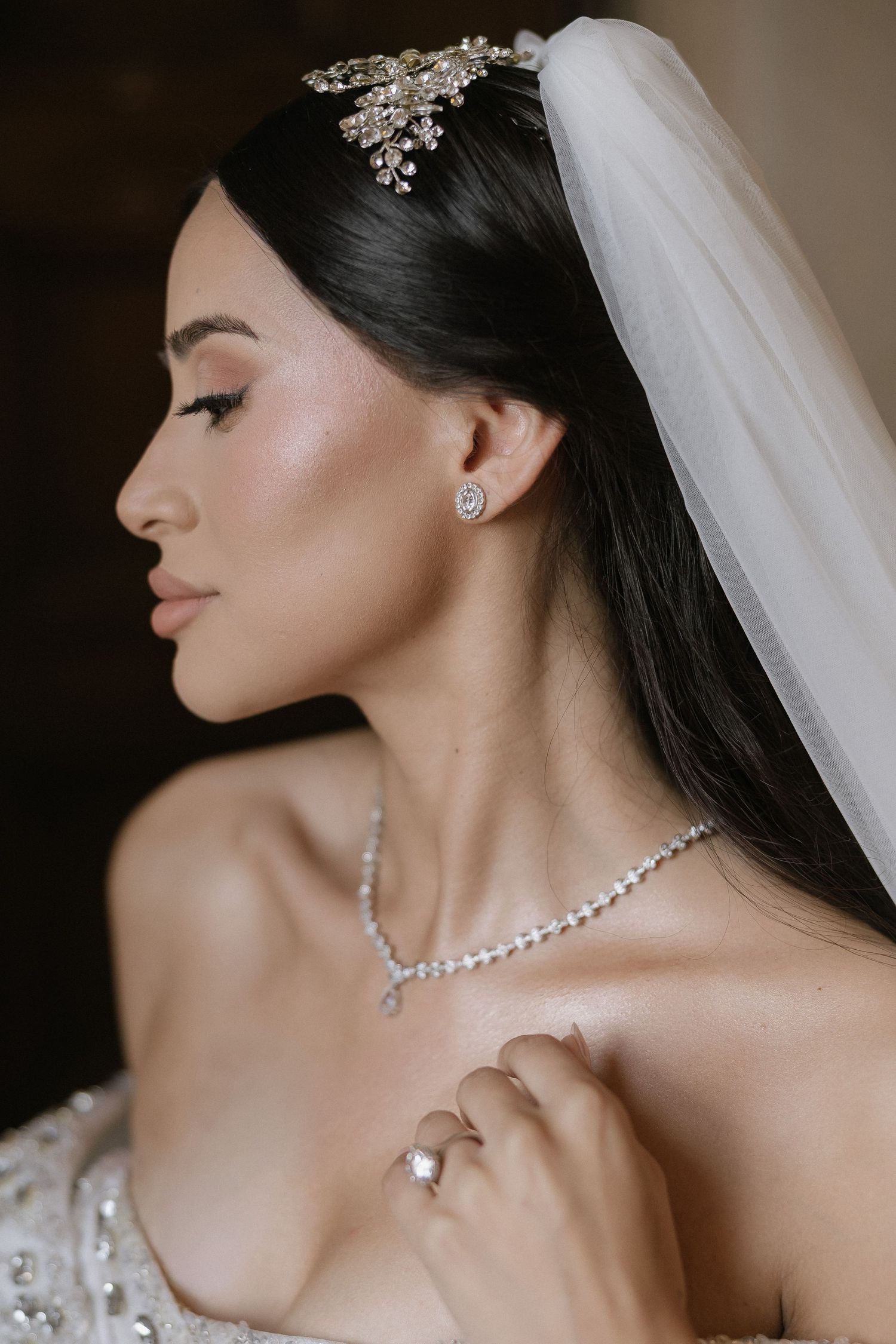Elegant bridal jewelry featuring a delicate crystal necklace and earrings set with matching floral hairpiece and veil.