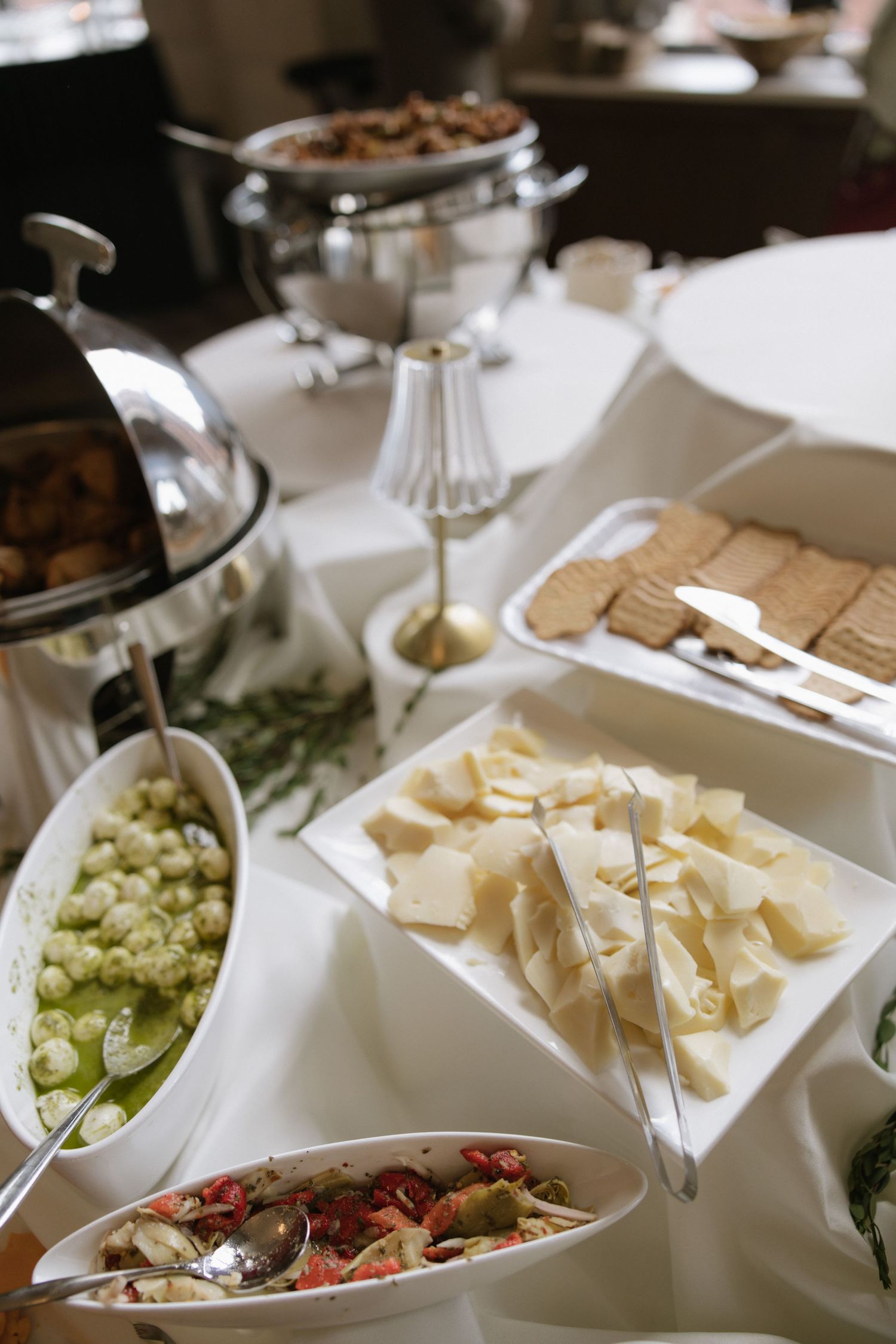 An elegant buffet spread featuring assorted cheeses, grapes, and appetizers arranged on white serving platters.