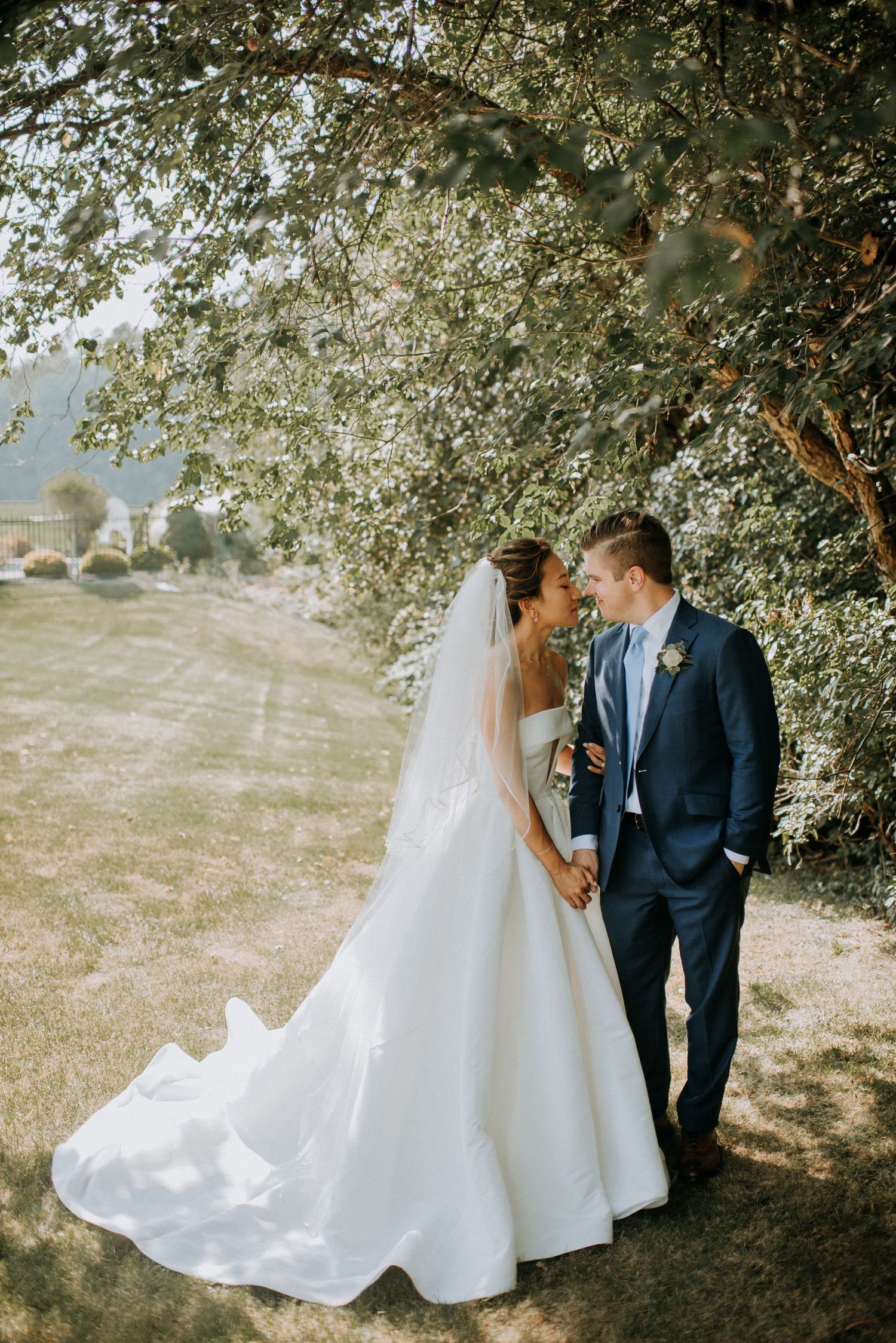 Newlyweds share romantic moments under a tree in a series of elegant outdoor wedding photographs.