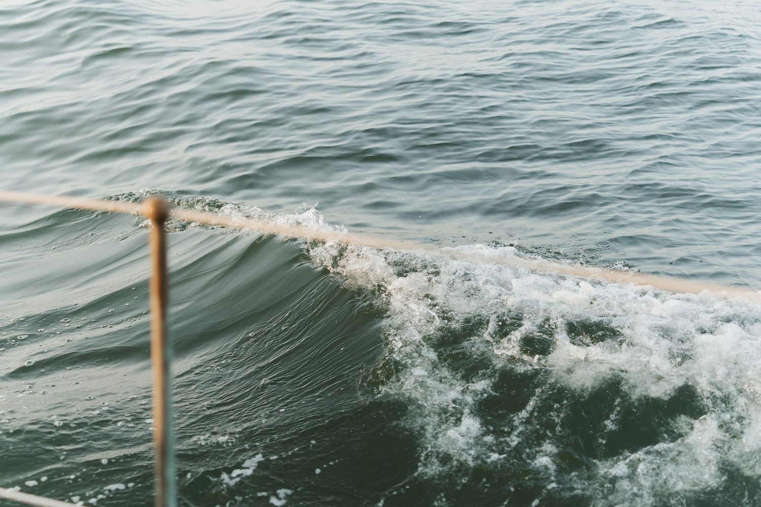 A wooden pole or stick pierces through the surface of rolling ocean waves creating a dynamic splash effect.