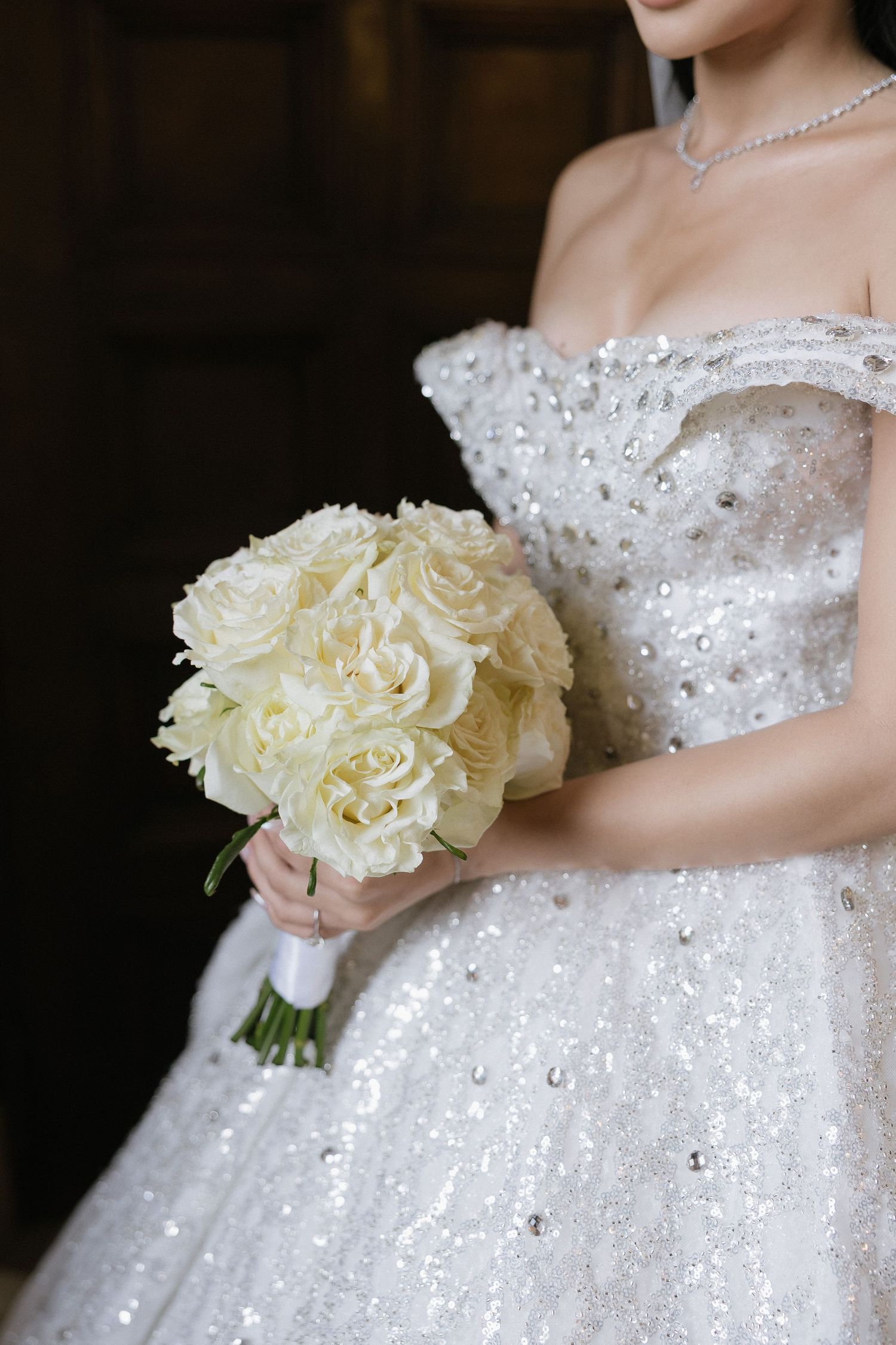 Close-up shots of a white wedding dress with sparkly details and a cream rose bouquet held by the bride.