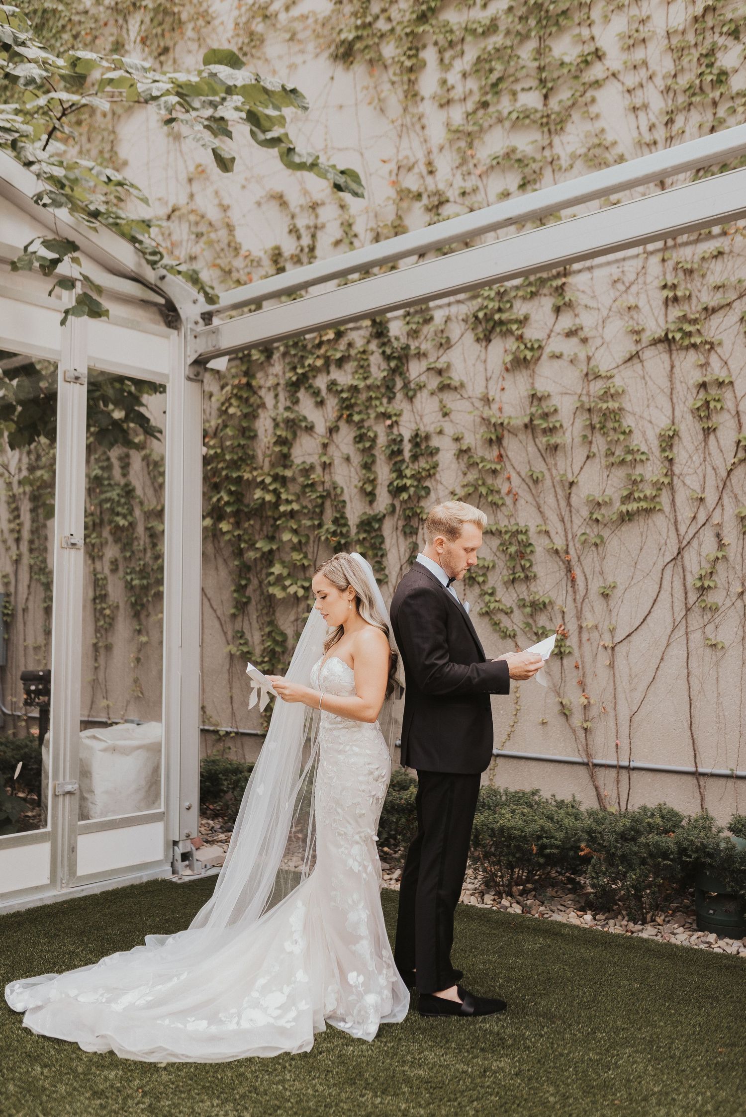 A couple reads letters to each other in a first look moment before their wedding ceremony in an outdoor garden setting.