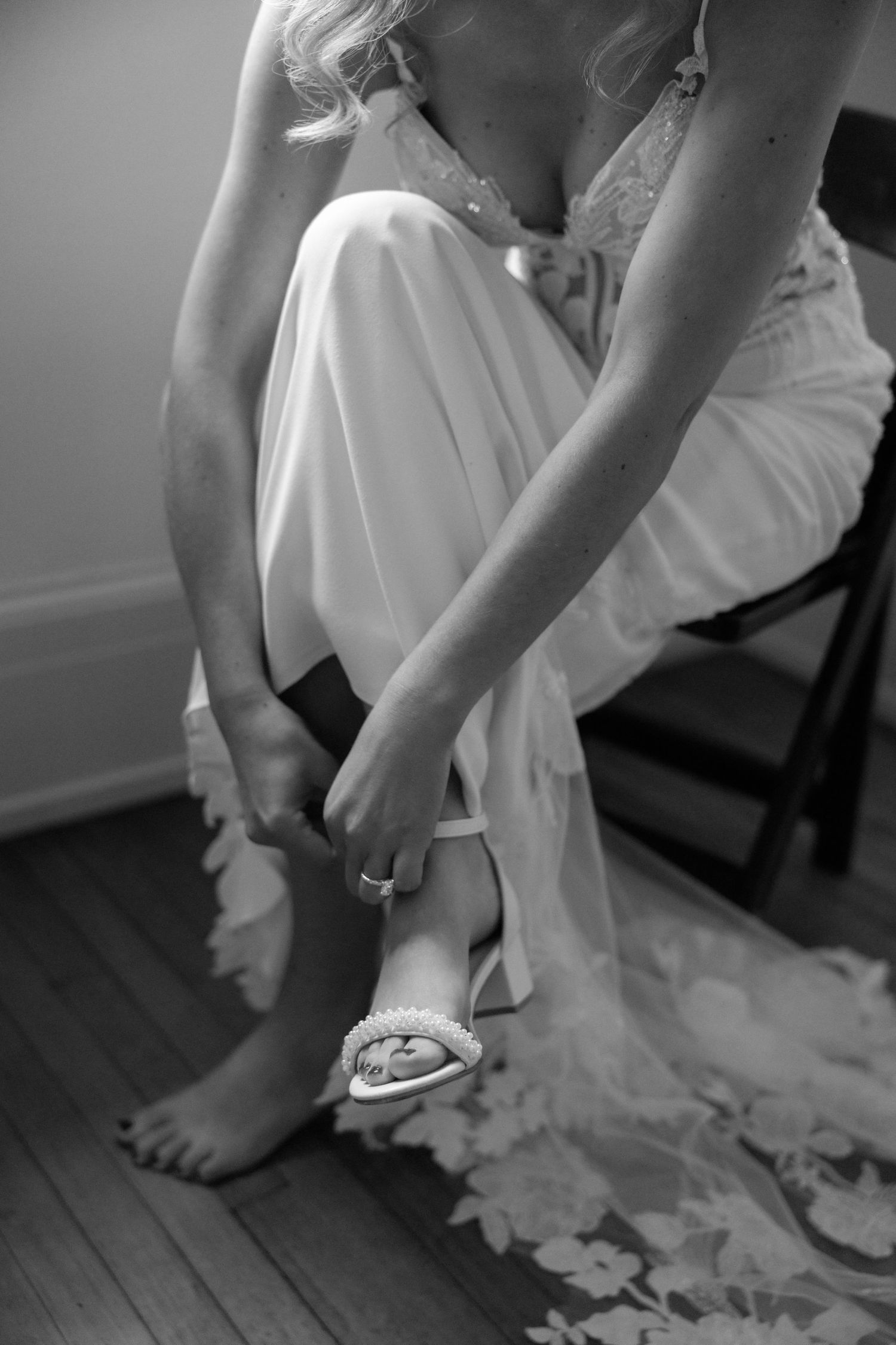 A series of black and white photographs showing close-up details of a bride getting ready with her wedding shoes and dress.