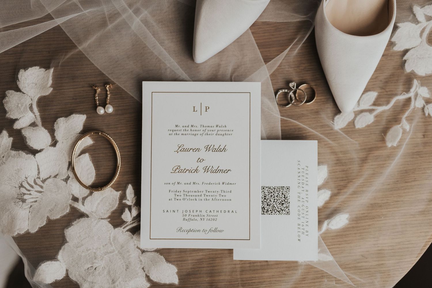 Wedding invitation suite with white floral details and elegant stationery arranged on a wooden surface.
