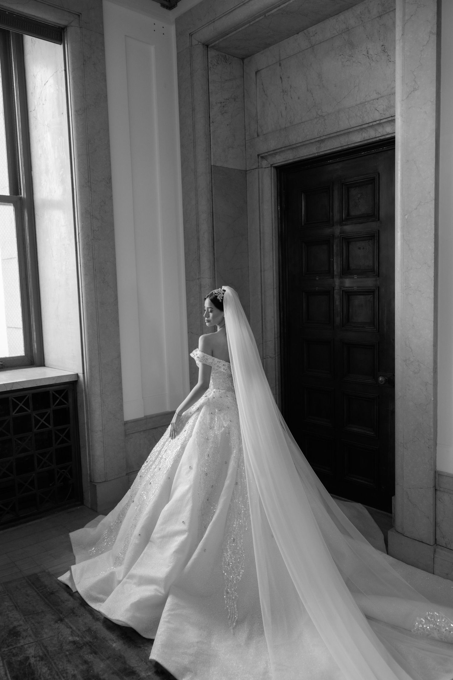 Flowing white sheer curtains billow dramatically in a minimalist concrete interior space with natural light streaming through windows.