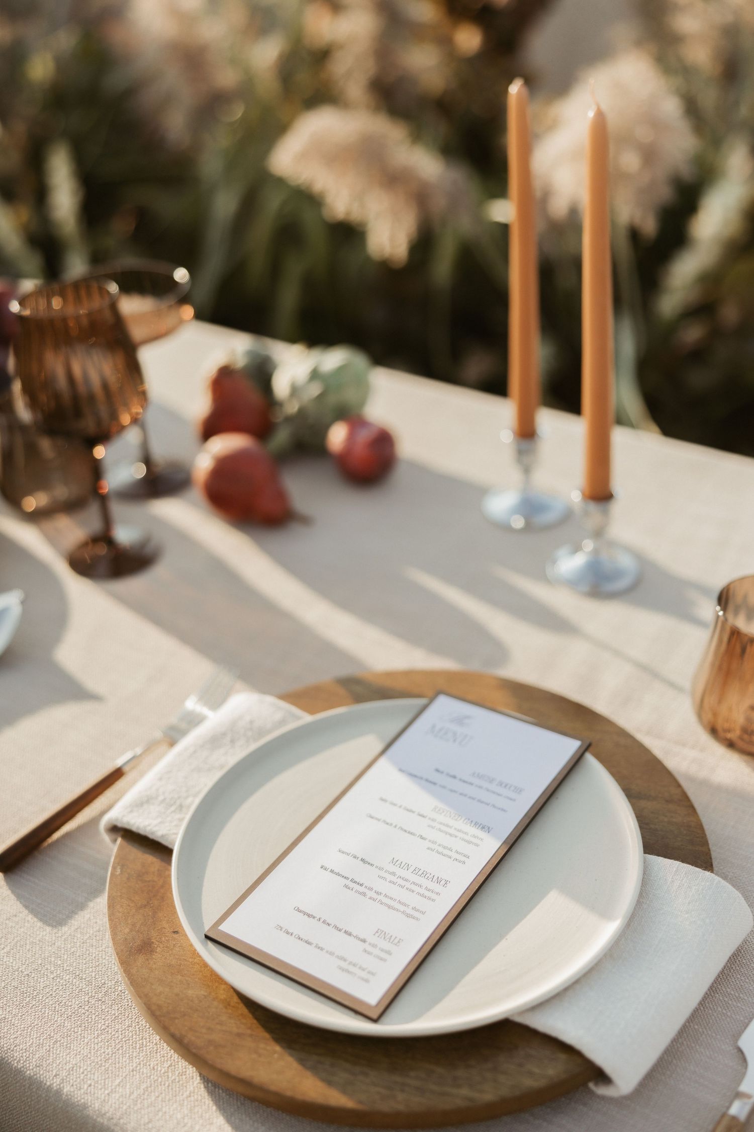 Elegant table setting with white plates on wooden chargers and menu cards for a formal dining event.