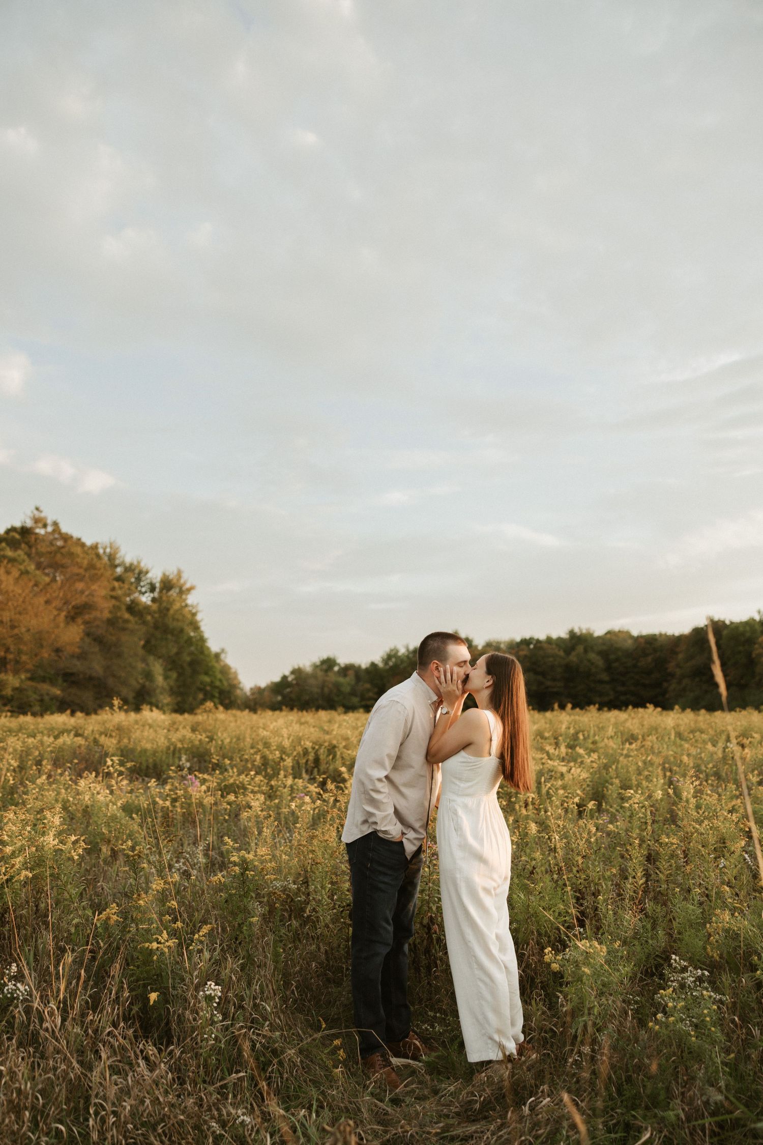 A romantic couple shares tender moments in a sunlit wildflower field during golden hour.