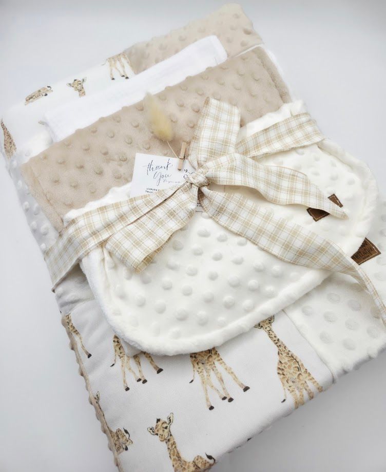 Soft giraffe print baby blanket with cream minky dot fabric, tied with a tan gingham bow and thank you tag.