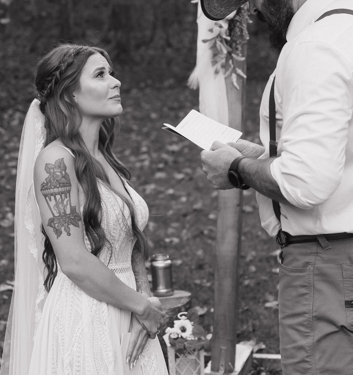 A wedding ceremony in progress with a couple exchanging vows in a black and white outdoor setting.