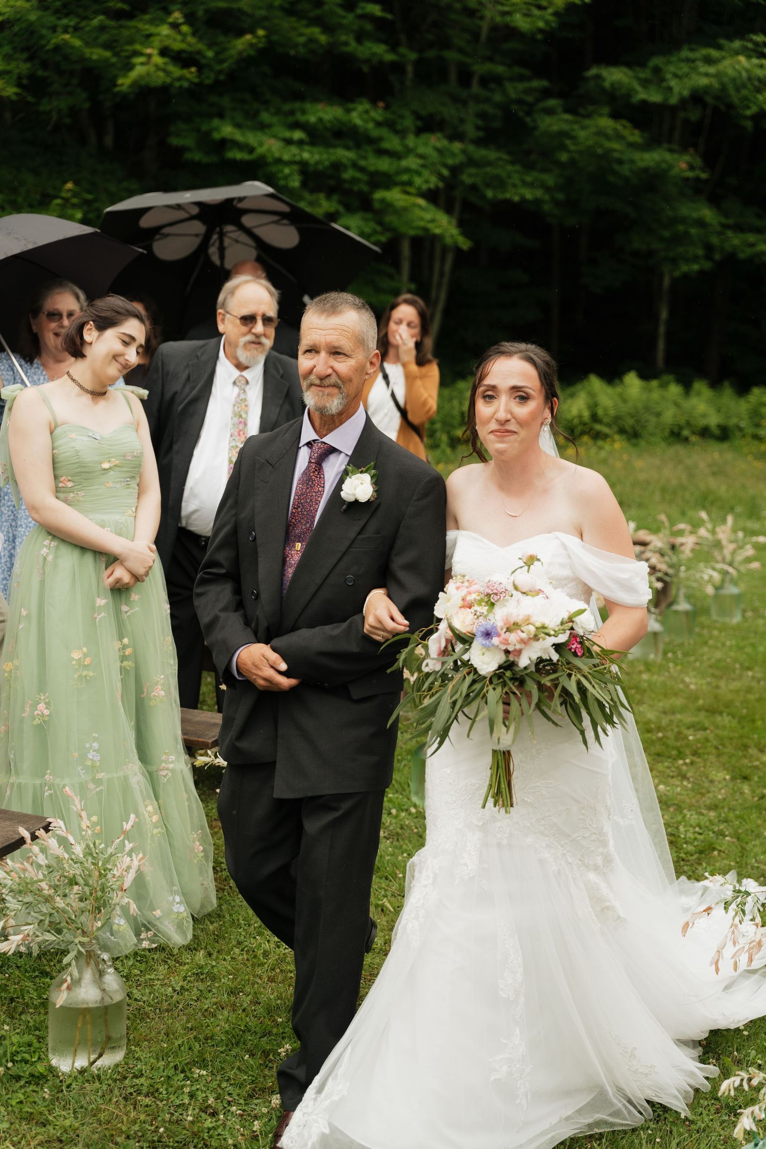 Wedding party poses under trees during outdoor ceremony with floral decorations.