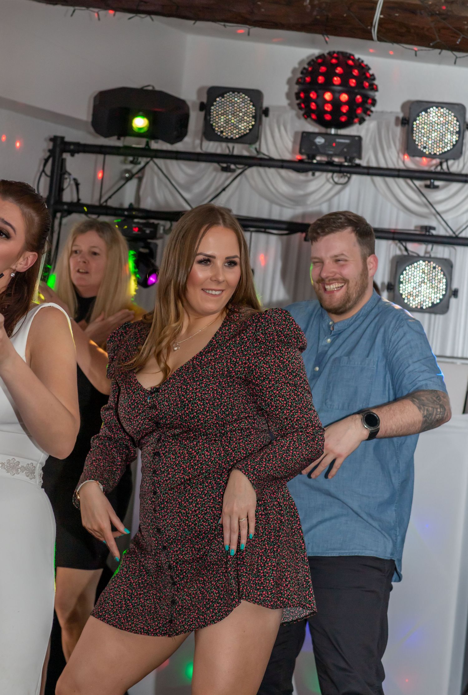 A group of people dancing and posing together at a party with colorful disco lights in the background.
