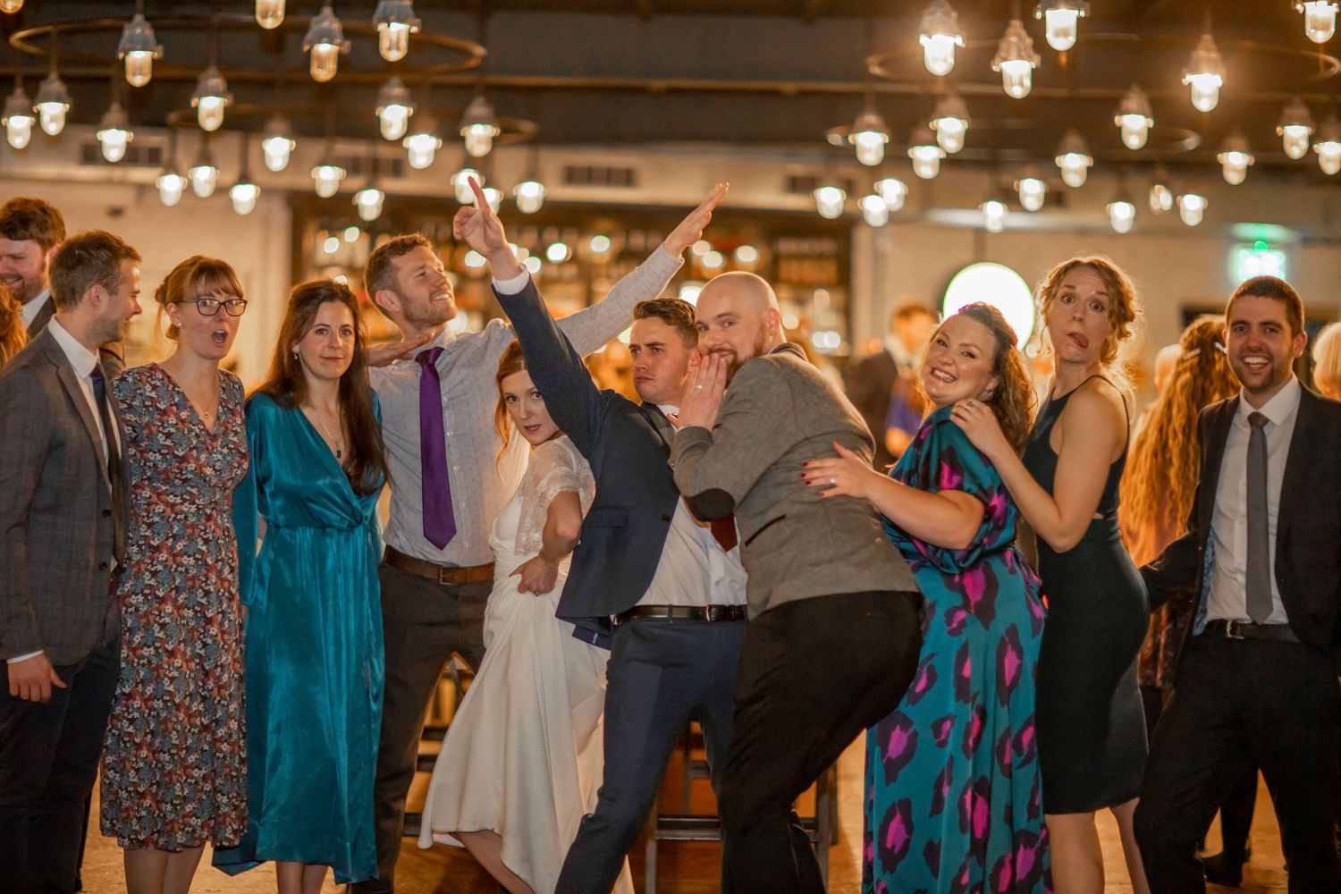 Wedding reception venue with warm glowing pendant lights and dancing guests.