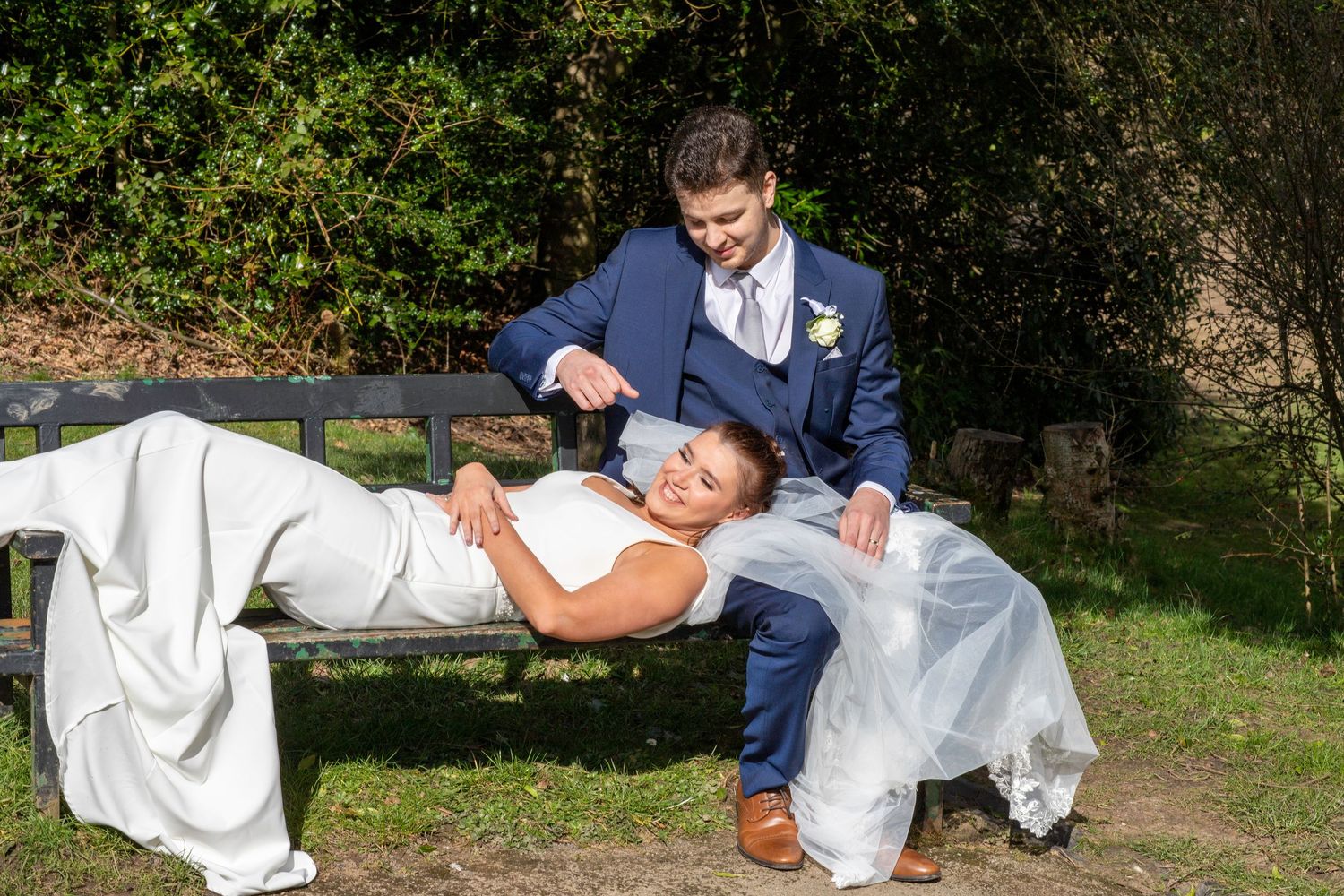 A playful wedding dip pose captured in a sunny garden setting.