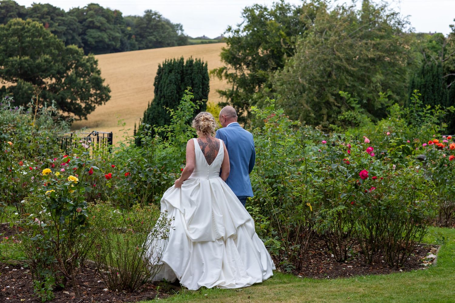 A couple poses among colorful garden flowers on their wedding day.