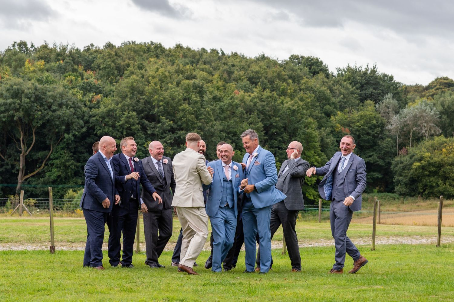 A line of guests lying on the ground in a grassy field for a creative wedding photo.