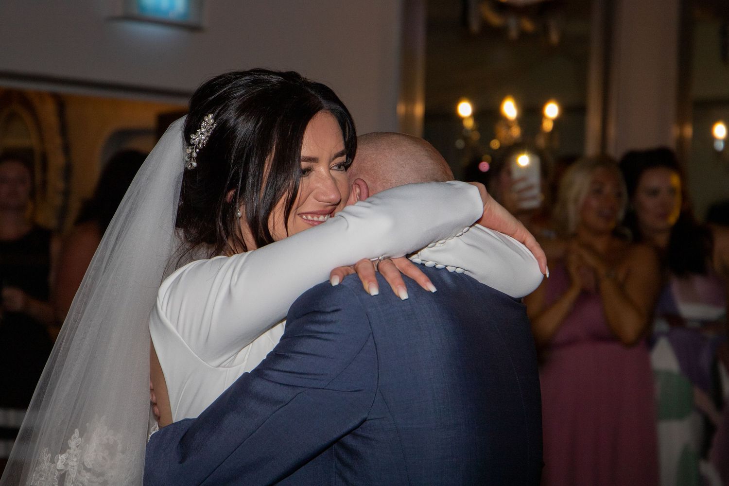 Dark reception venue with couples sharing intimate dance moments under ambient lighting.