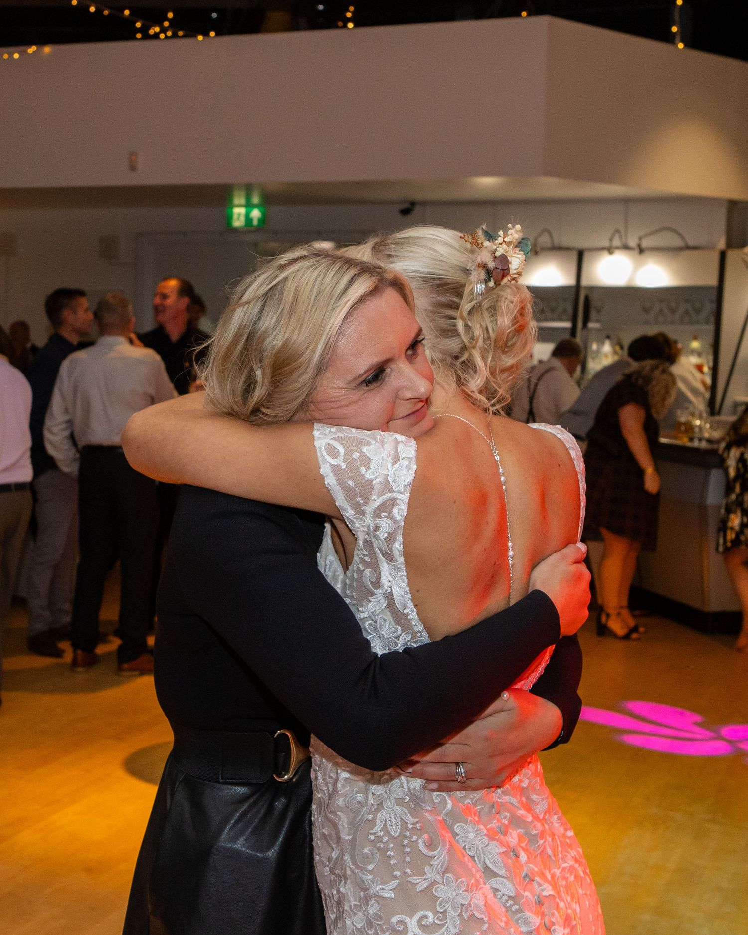 Dancers in formal attire perform at an indoor event with string lights and warm lighting in the background.