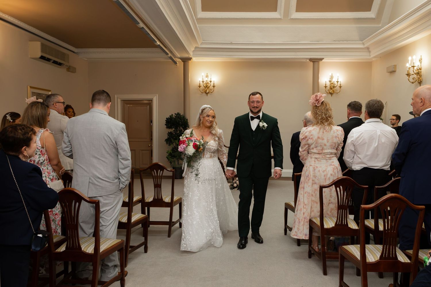 Bride and groom walk hand in hand down the aisle after their wedding ceremony in an elegant venue.