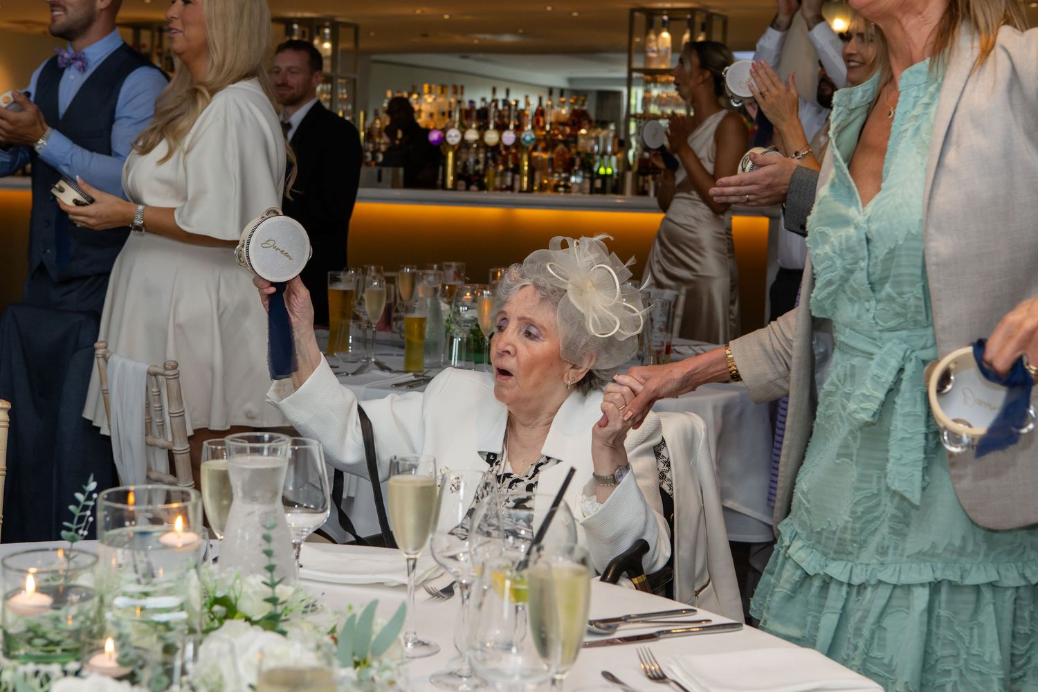 People gathered around elegant dining tables at an upscale event with crystal glassware and formal table settings.
