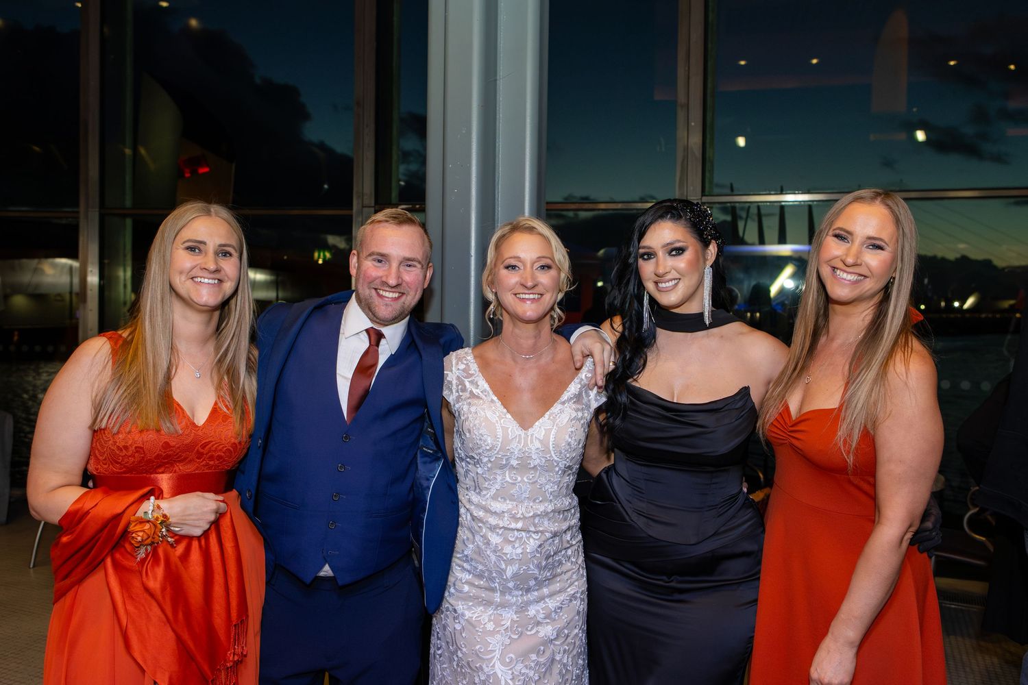 A group of people in formal attire posing together at an evening event with red and blue outfits.