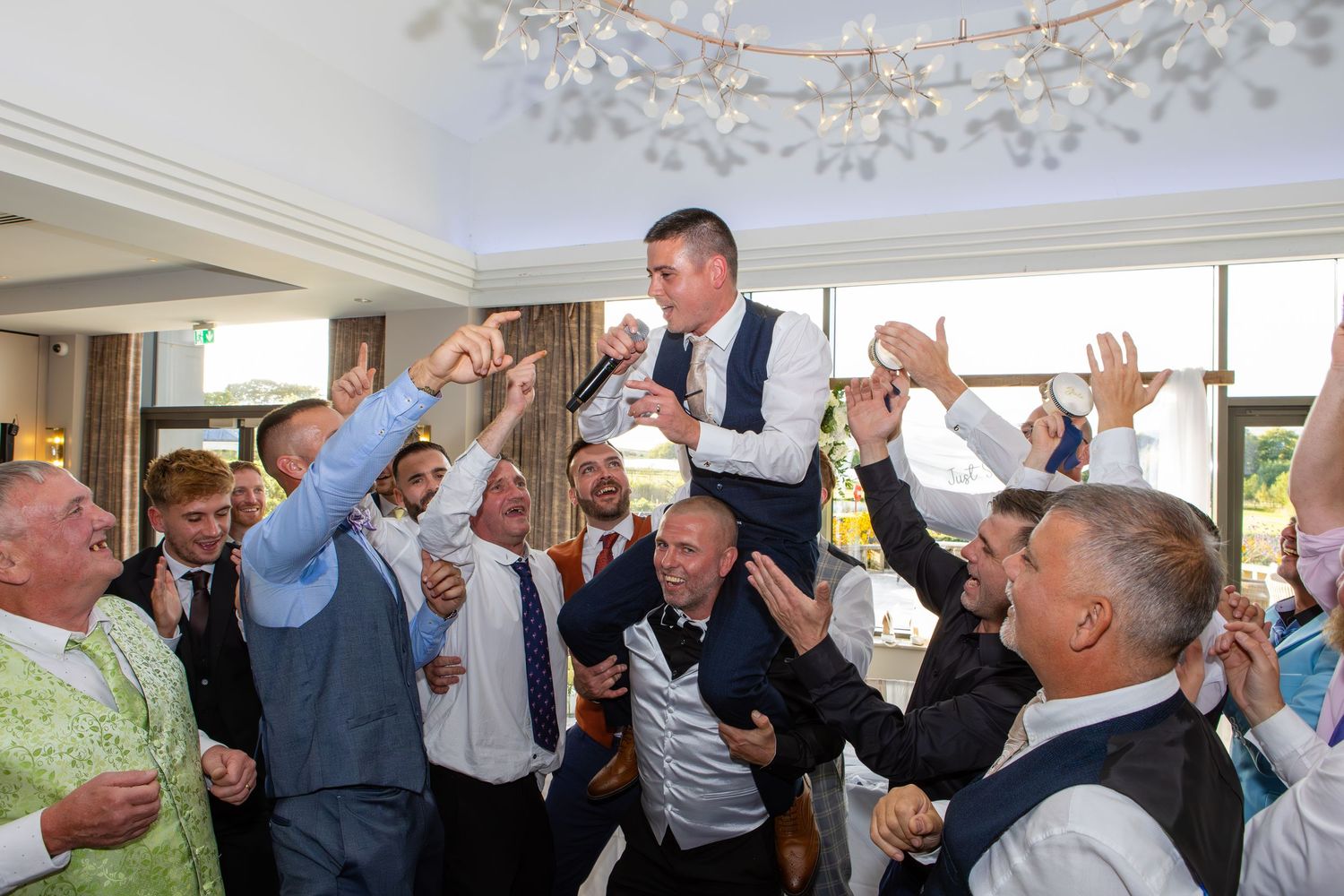 A group of people with raised arms celebrating at an outdoor event under a white tent.