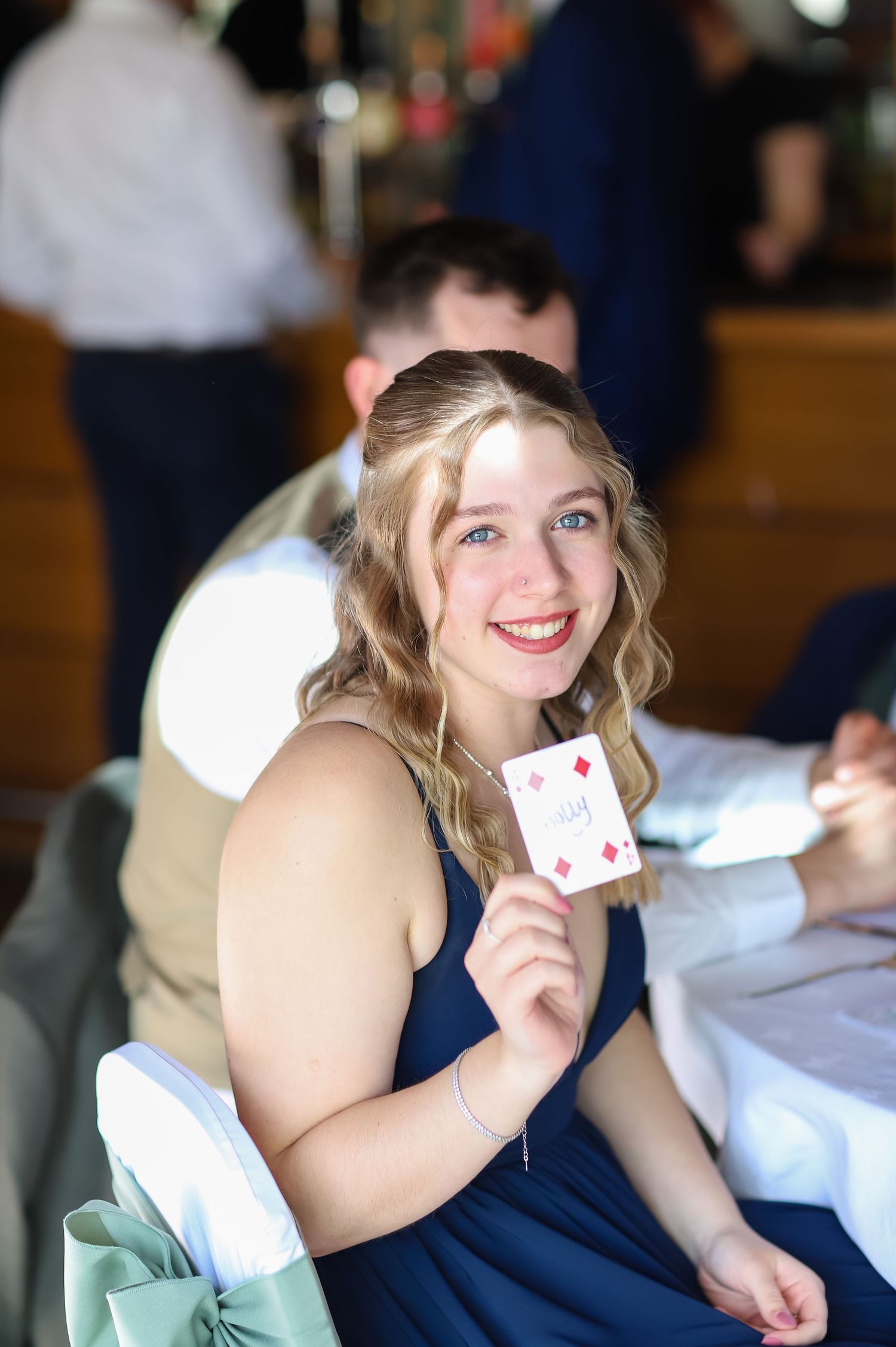 Guest holding up a playing card while seated at a reception table.