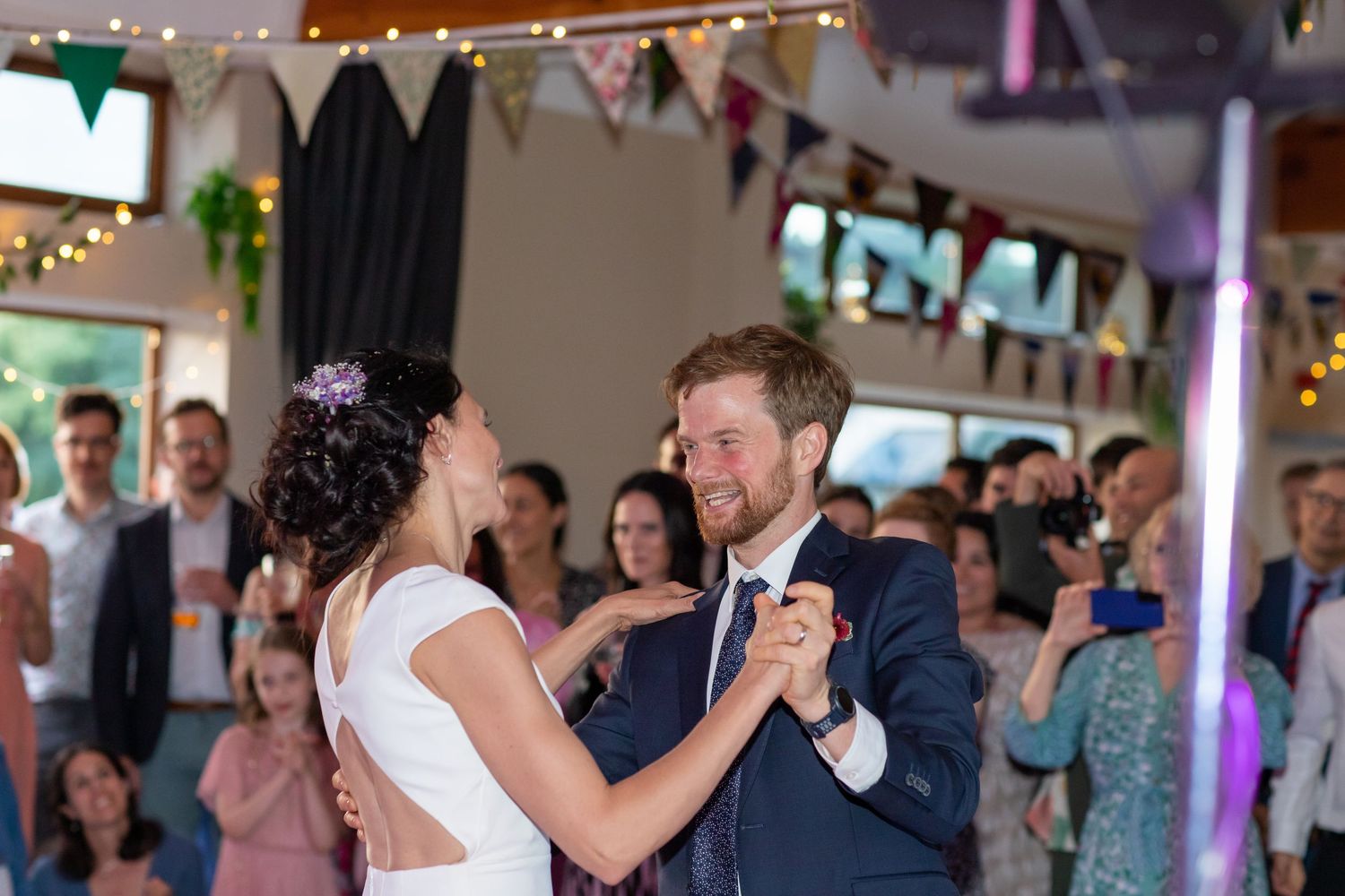 A couple shares their first dance under string lights at their wedding reception.
