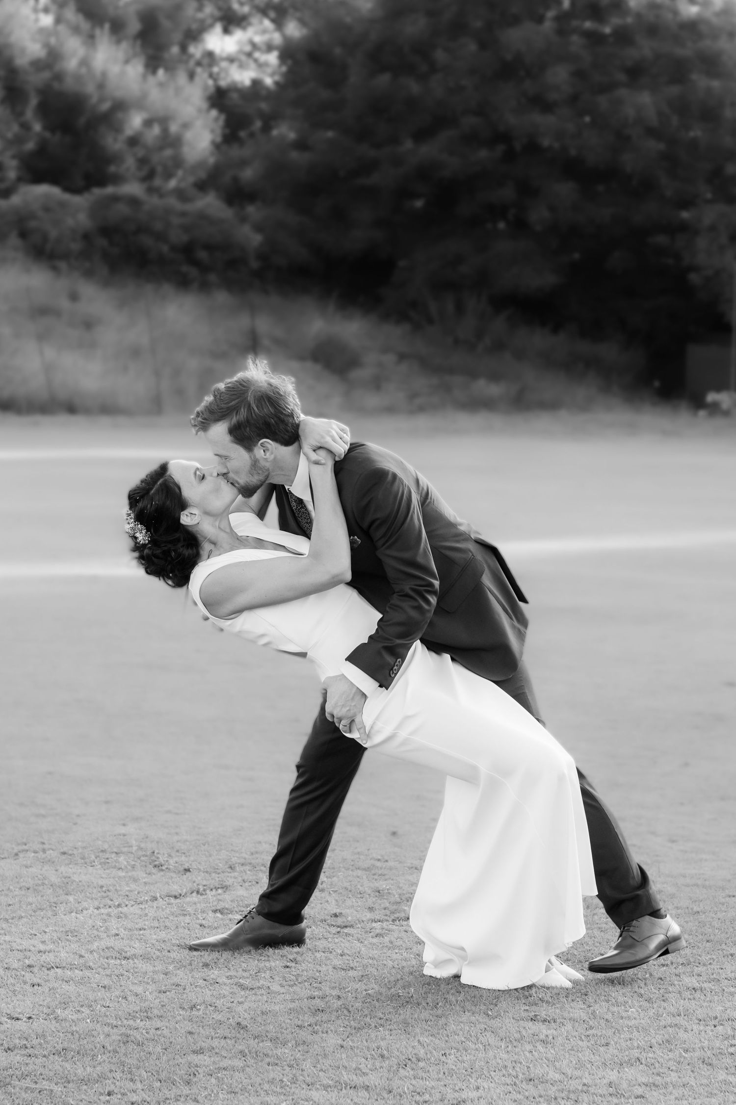 A dramatic black and white photo of a couple performing a romantic dip pose.
