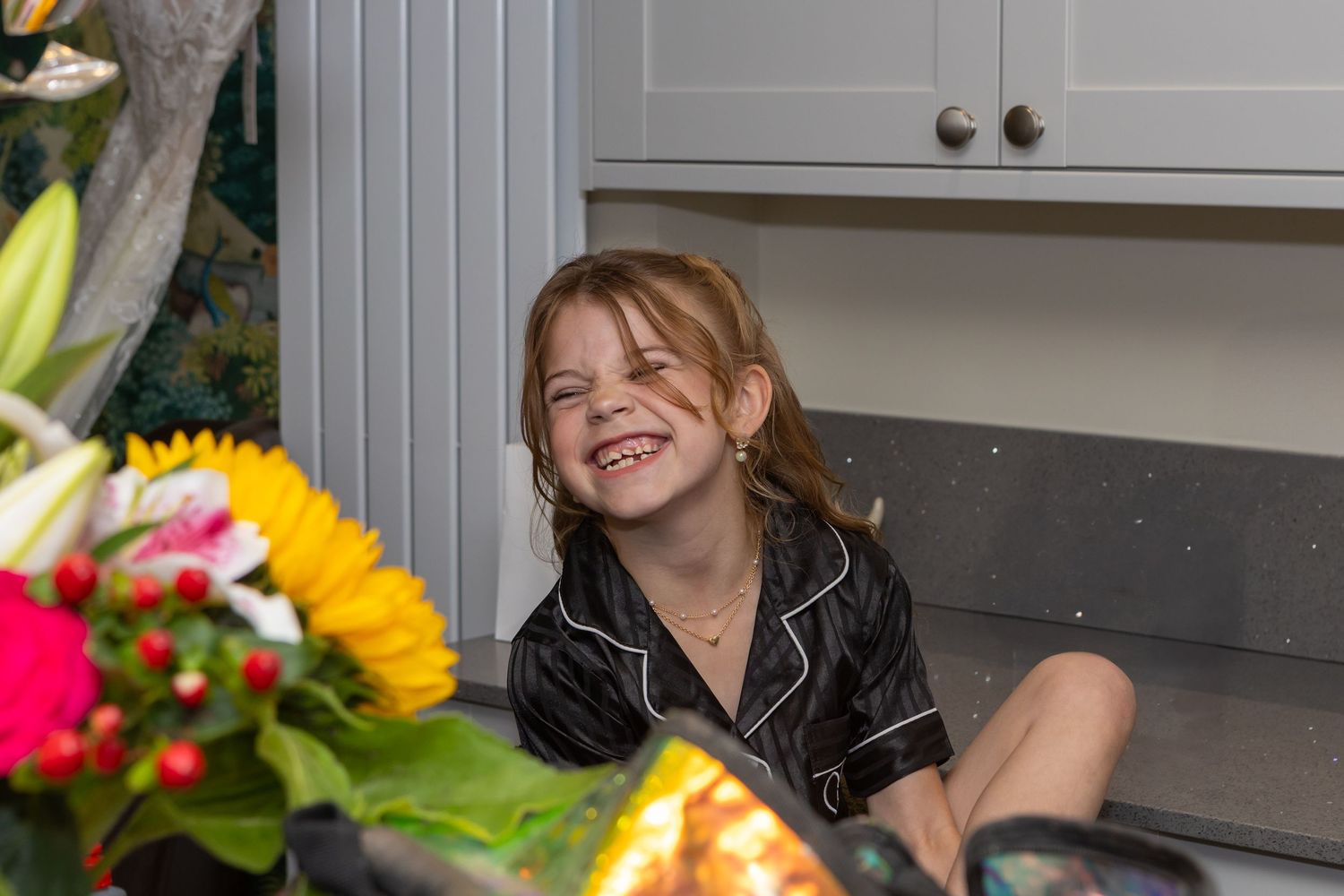 A joyful expression next to a bright floral arrangement with sunflowers in a kitchen setting.