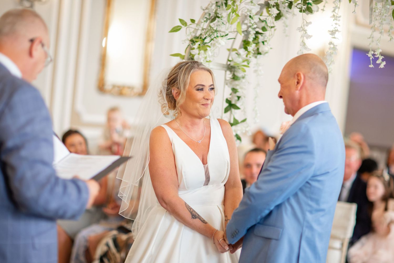 A couple shares their first dance beneath elegant floral decorations at their reception.