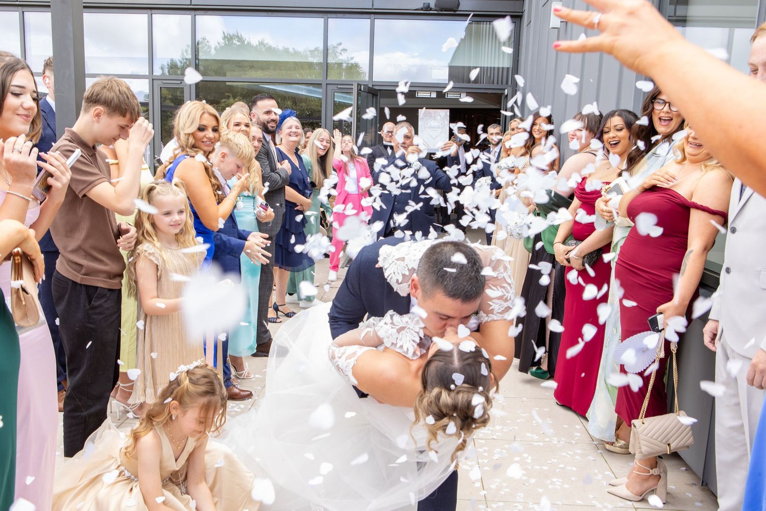 Wedding guests blow bubbles and celebrate as newlyweds walk through a joyful crowd during an outdoor ceremony.