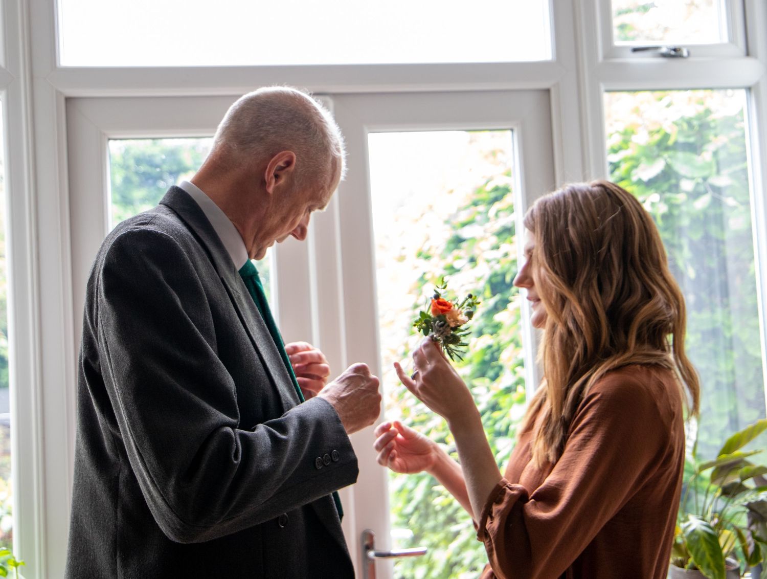 Silhouettes of guests by bright windows during an elegant indoor wedding reception.