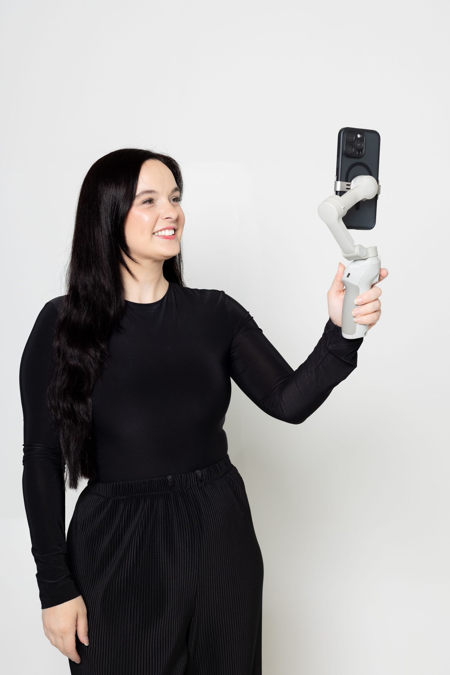 Photographer demonstrating mobile phone gimbal device in studio setting.