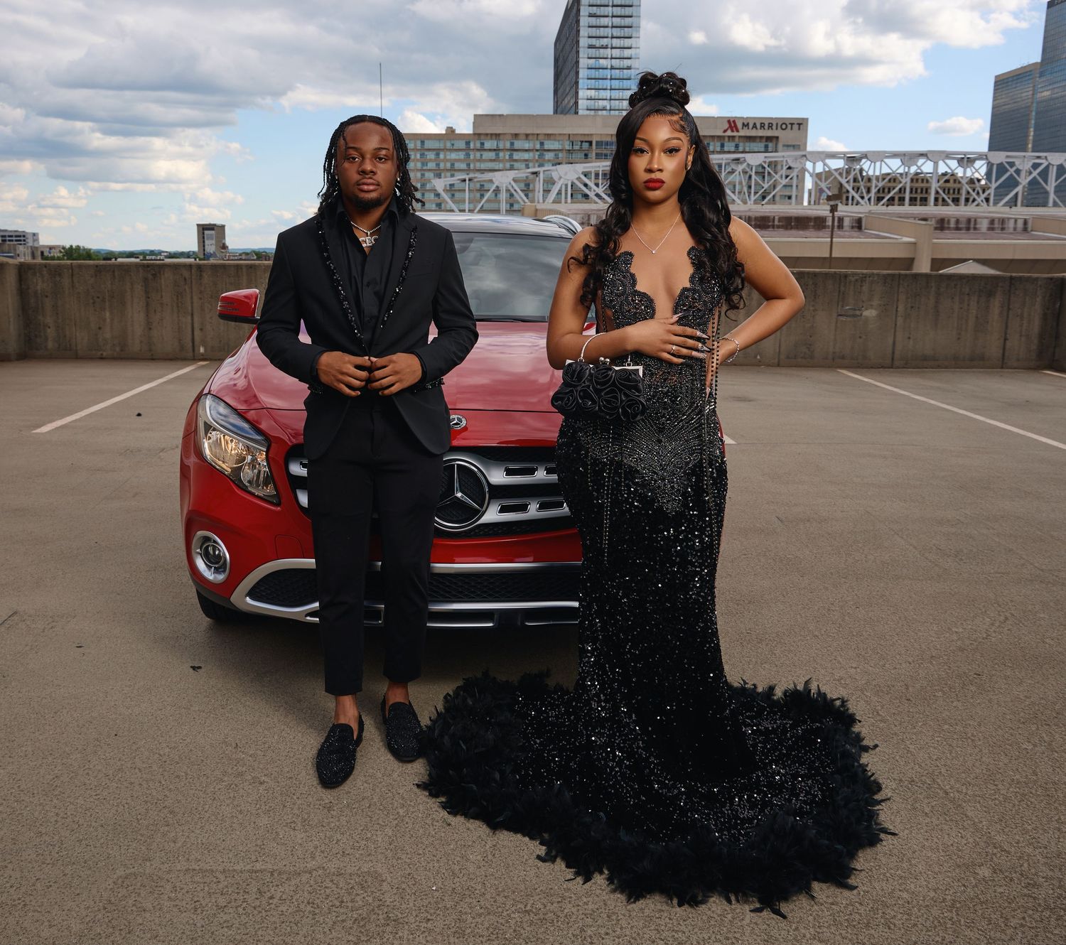 A couple poses together in front of a red car in an urban parking garage, creating a series of candid moments.