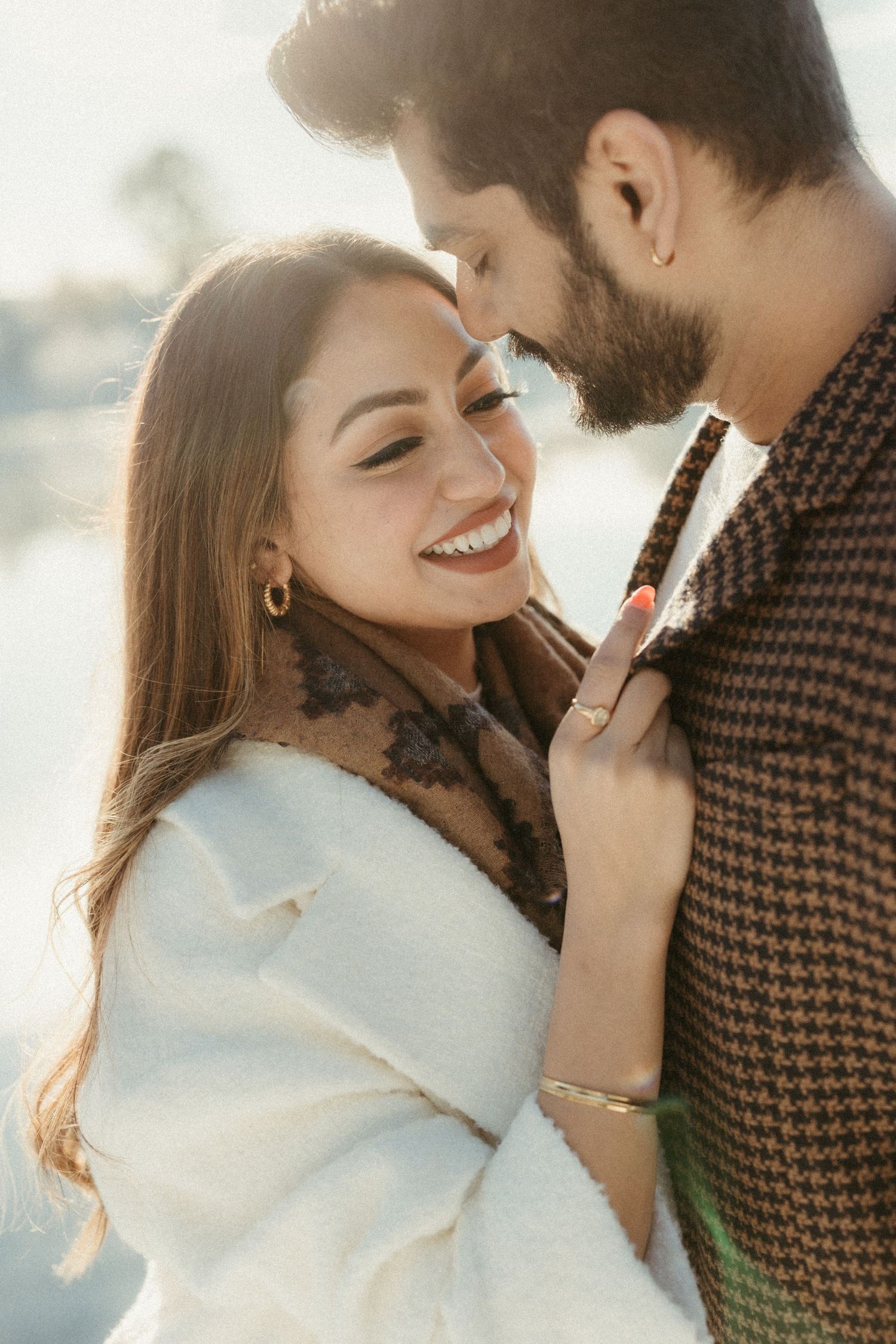 Close-up portrait of couple sharing an intimate moment in winter outerwear during sunset.
