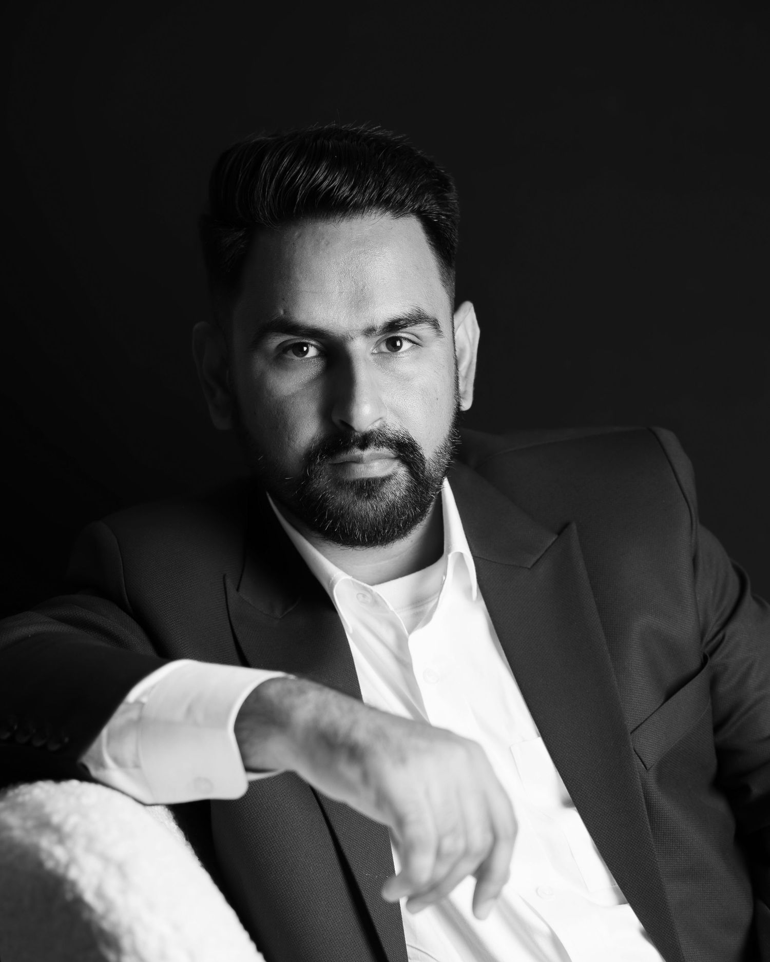 Dramatic black and white portrait of groom in formal attire.