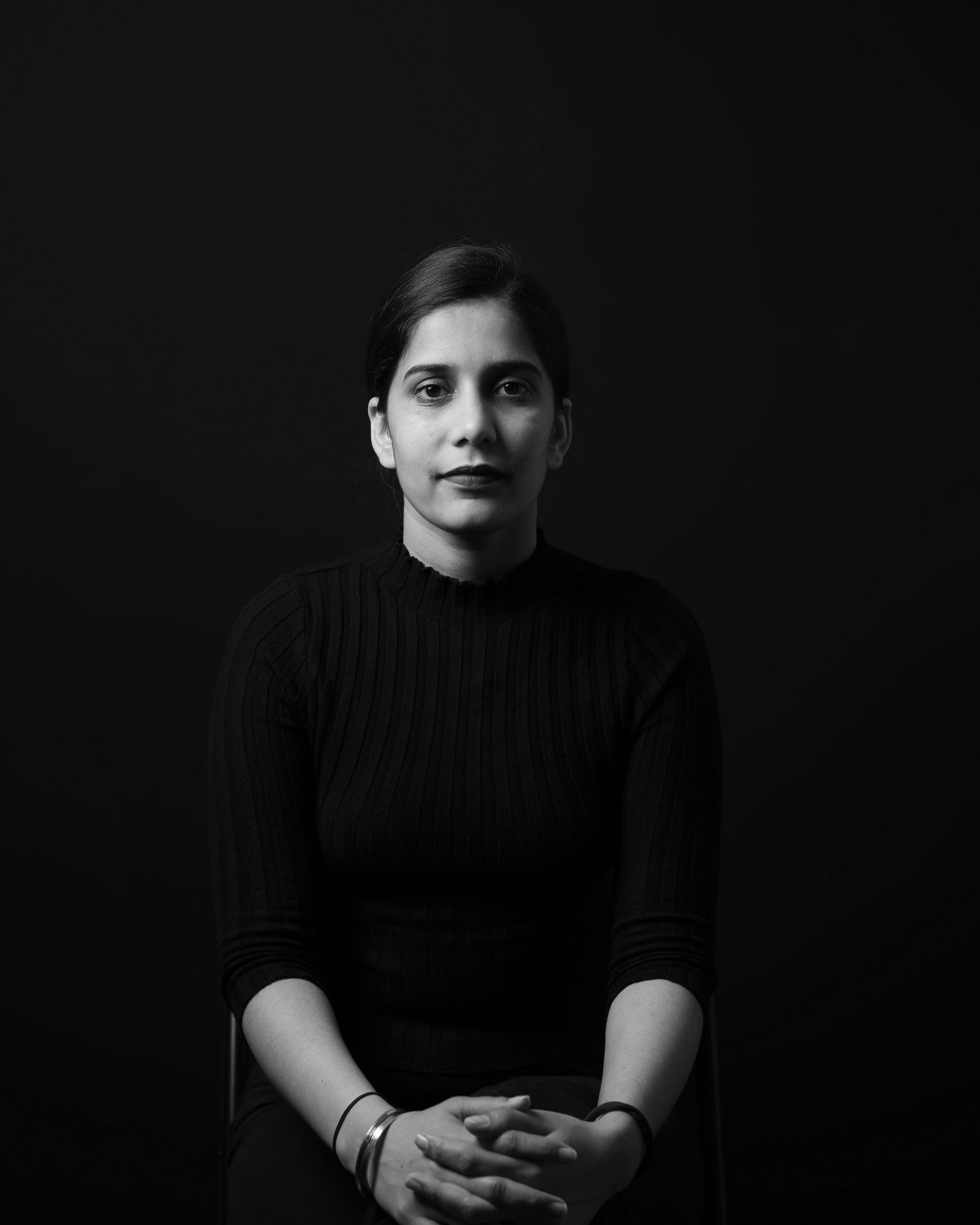 A series of black and white portraits showing a person in dark clothing against a black background.