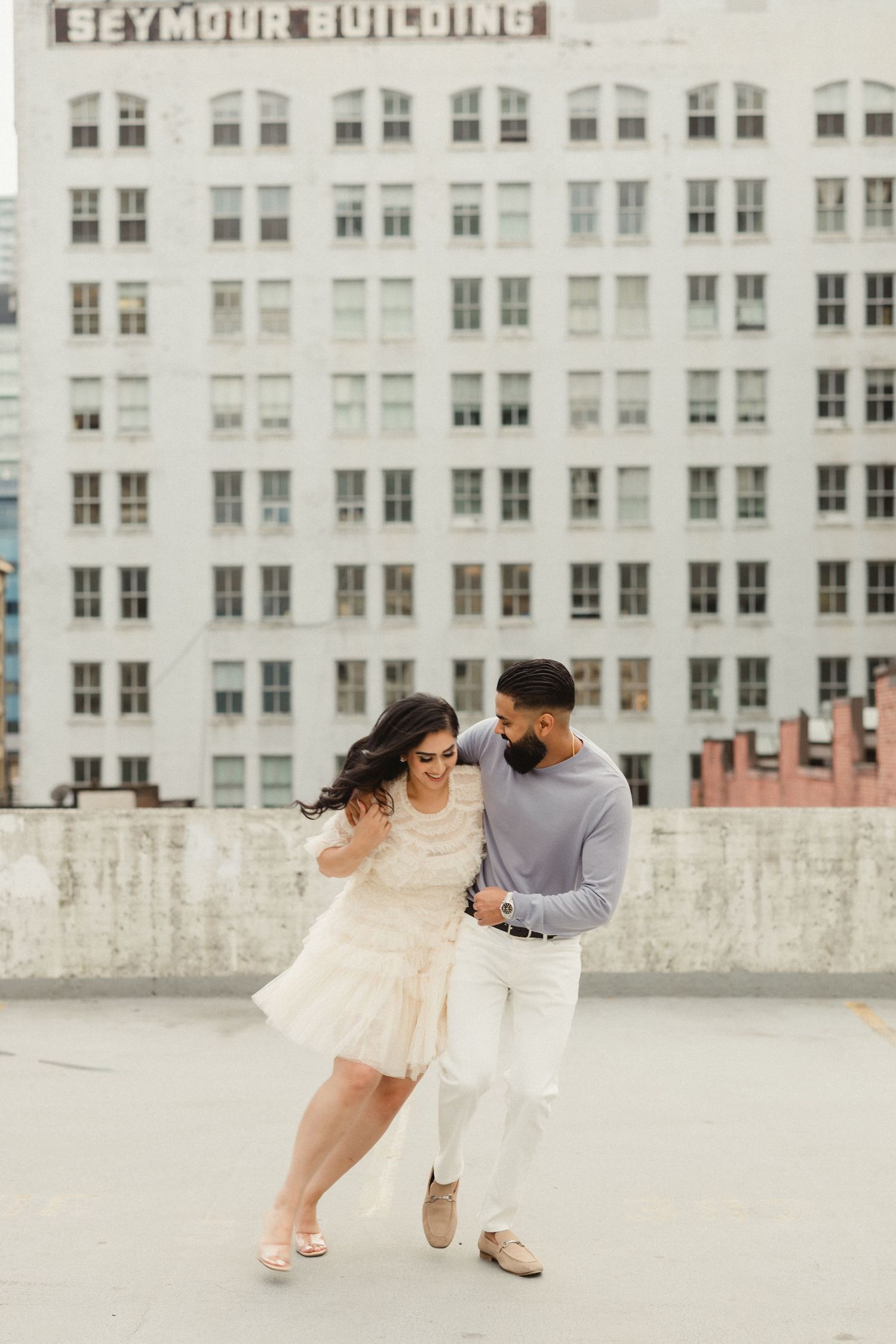 Couple dancing playfully in front of the historic Seymour Building.