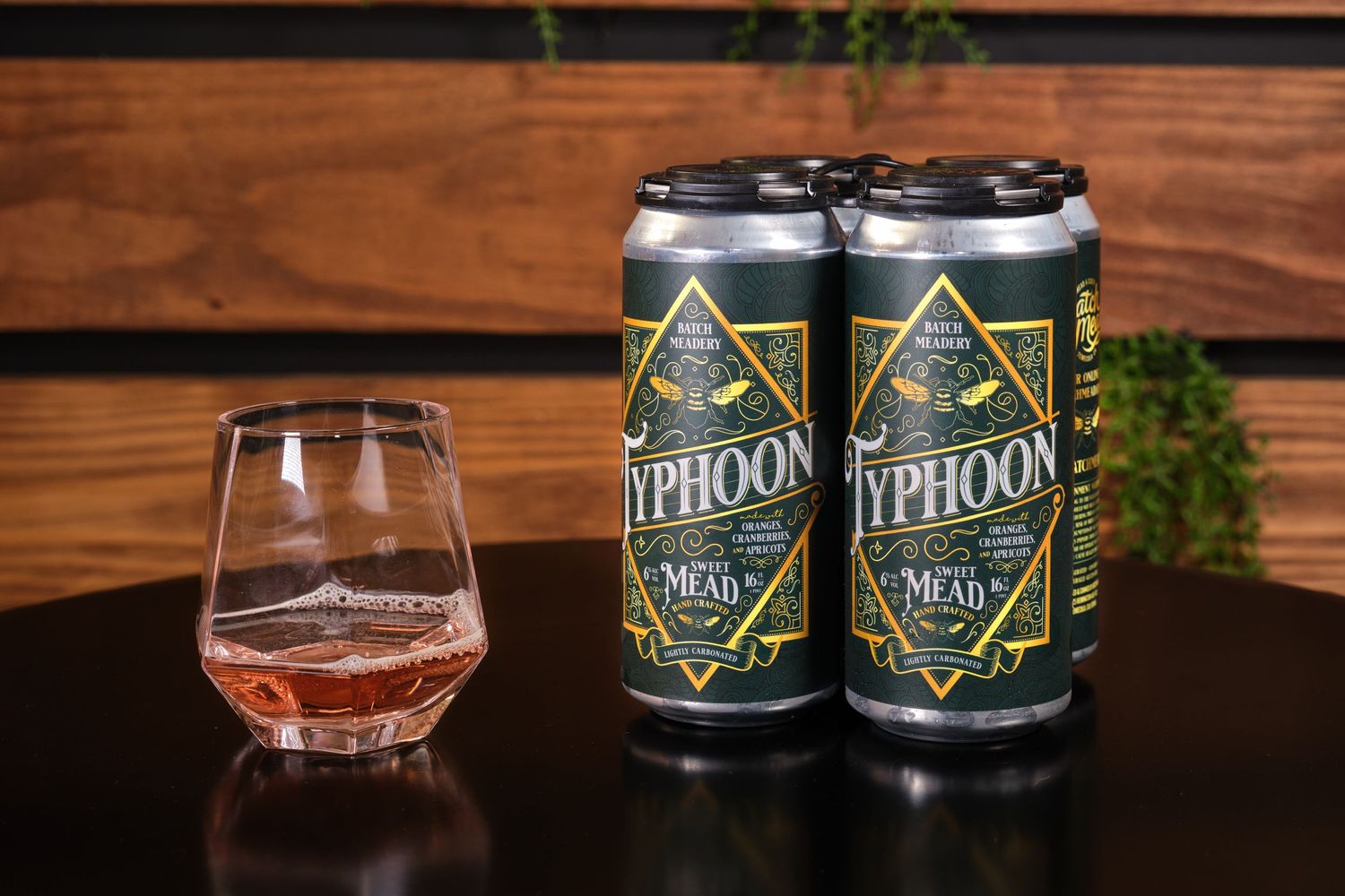 Two cans of Typhoon craft beer next to a glass on wooden surface.